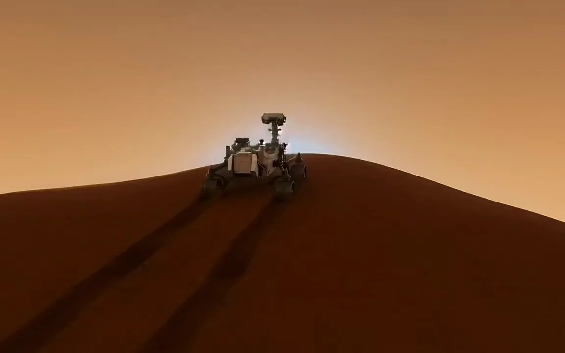 A six wheeled rover cresting a rust red dune on Mars at sunset