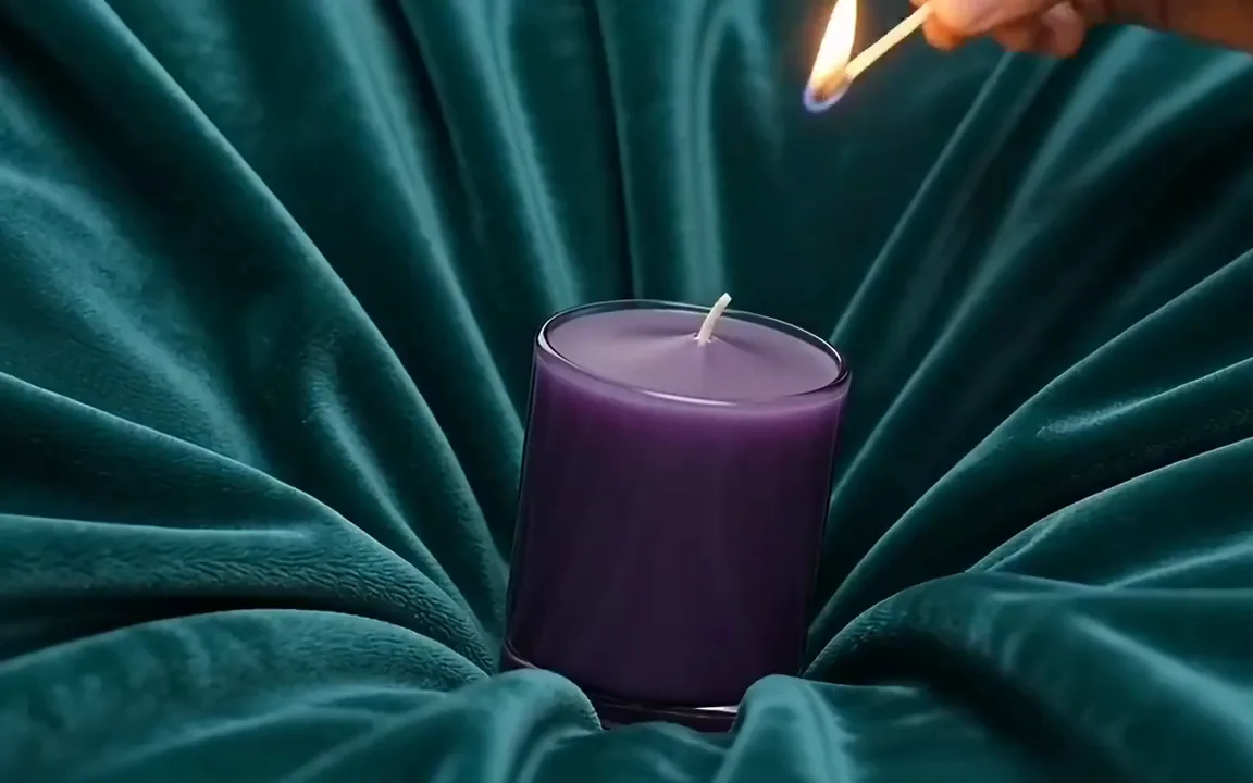 Seedance video of a match lighting a violet glass candle on teal velvet