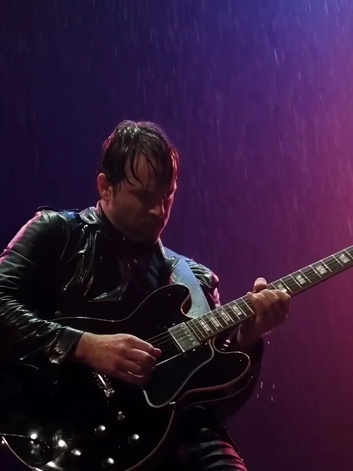 KI-generiertes Video eines Gitarristen, der unter violettem Bühnenlicht im Regen spielt