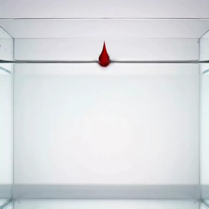 Una goccia d'inchiostro rosso che diventa un pesce rosso in un acquario di vetro