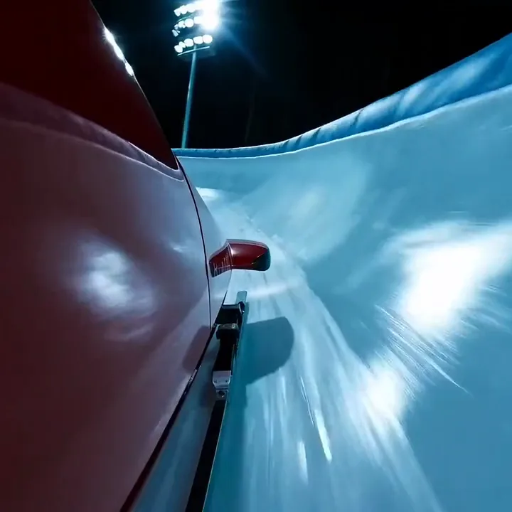 Close view of a red bobsled racing through a floodlit ice track at night