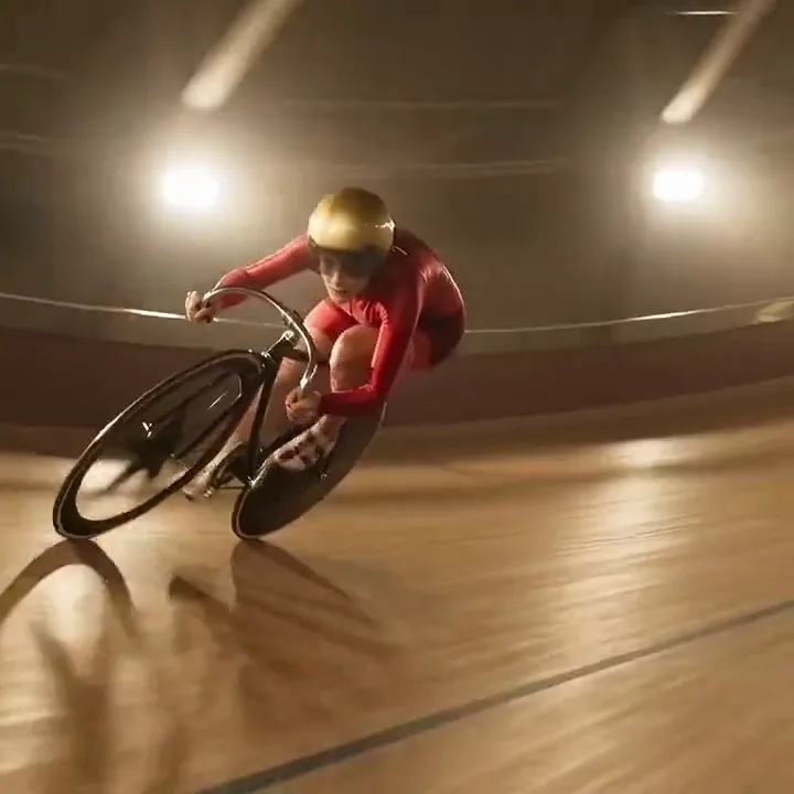 Wan 2.2 video of a track cyclist in red and a gold helmet sweeping down the velodrome banking