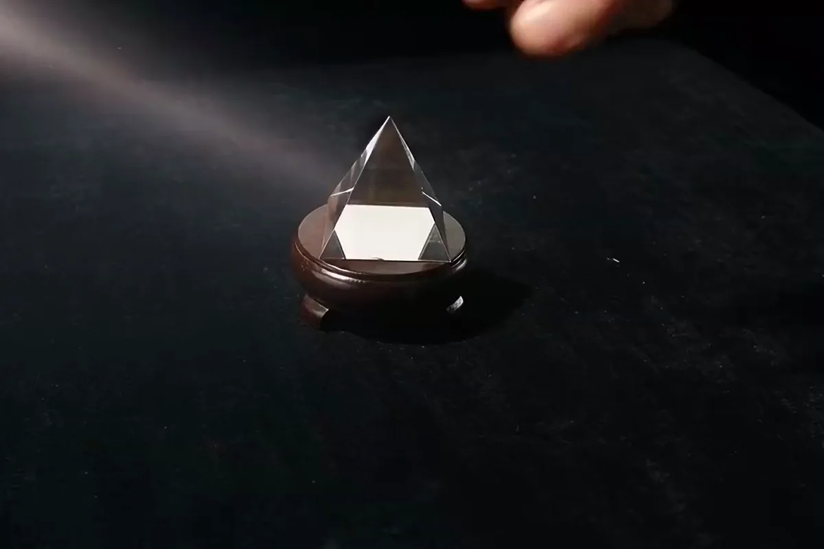 AI video generator clip of a hand turning a crystal prism that throws a rainbow fan across black velvet