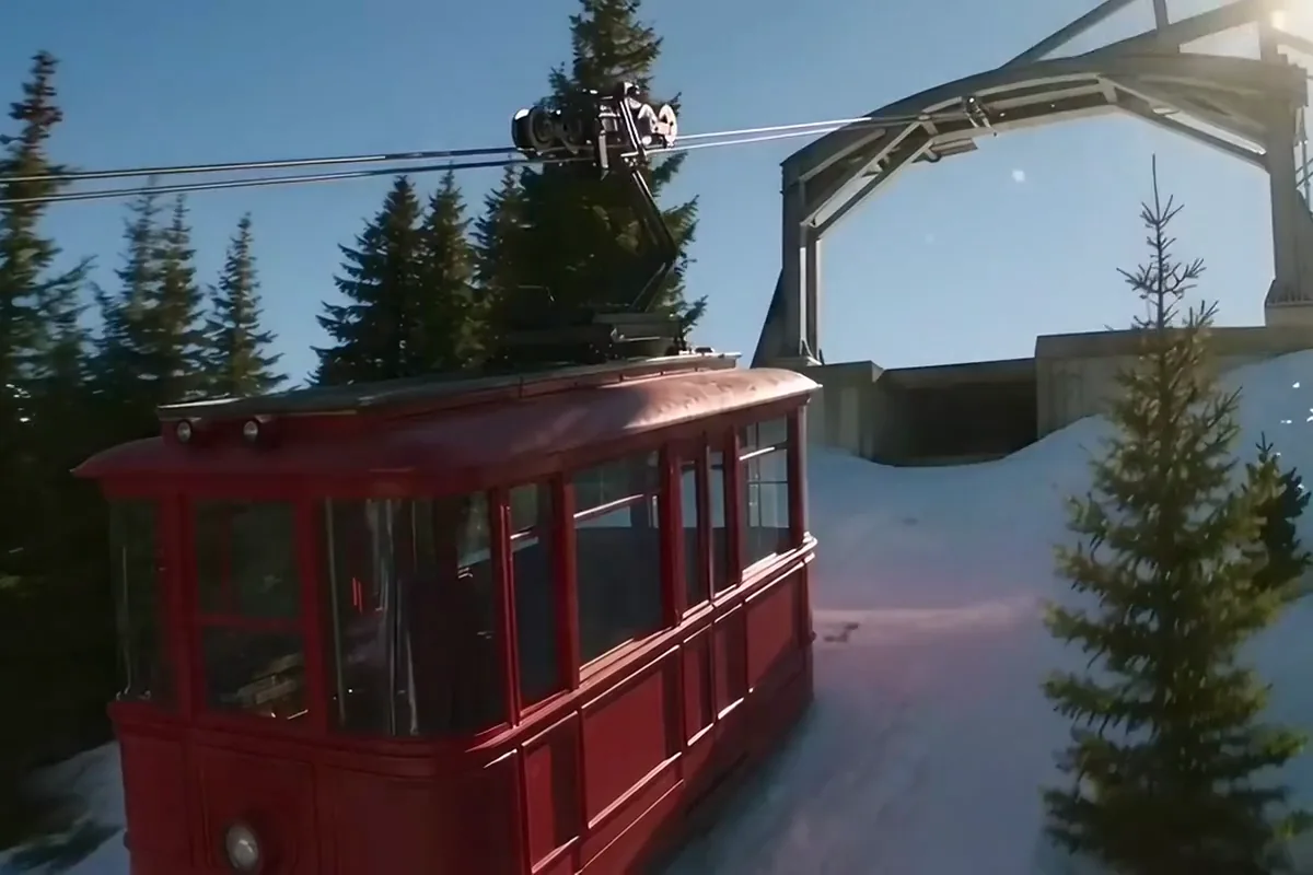 AI video of a red cable car pulling into its summit station above a turquoise lake