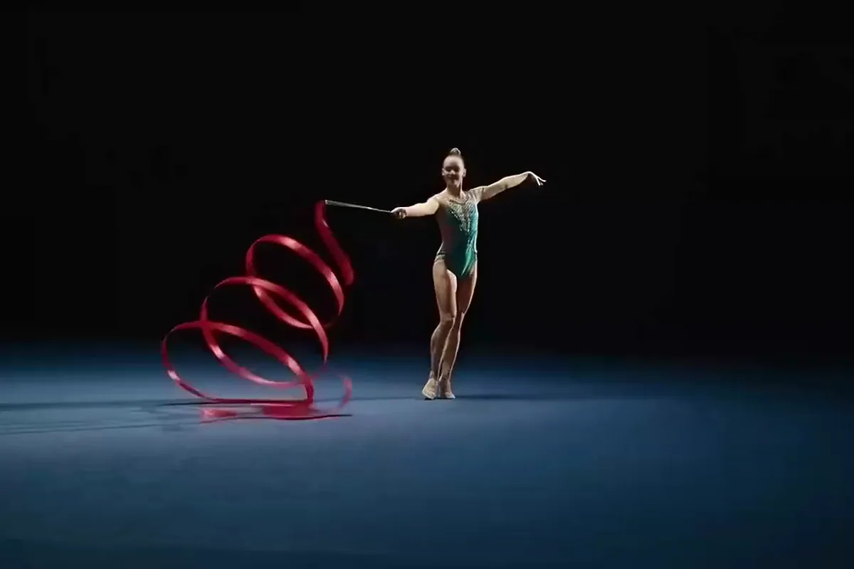 AI generated video of a gymnast in teal turning as her red ribbon spirals around her