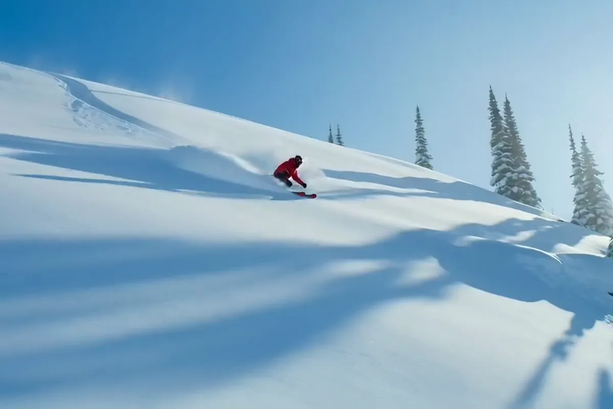 Kling AI video of a skier in red carving down a sunny powder slope between pines