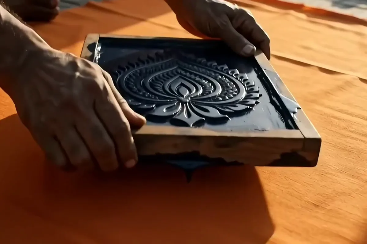 Wan 2.2 video of a carved block pressed on saffron cotton and lifted to show an indigo paisley print