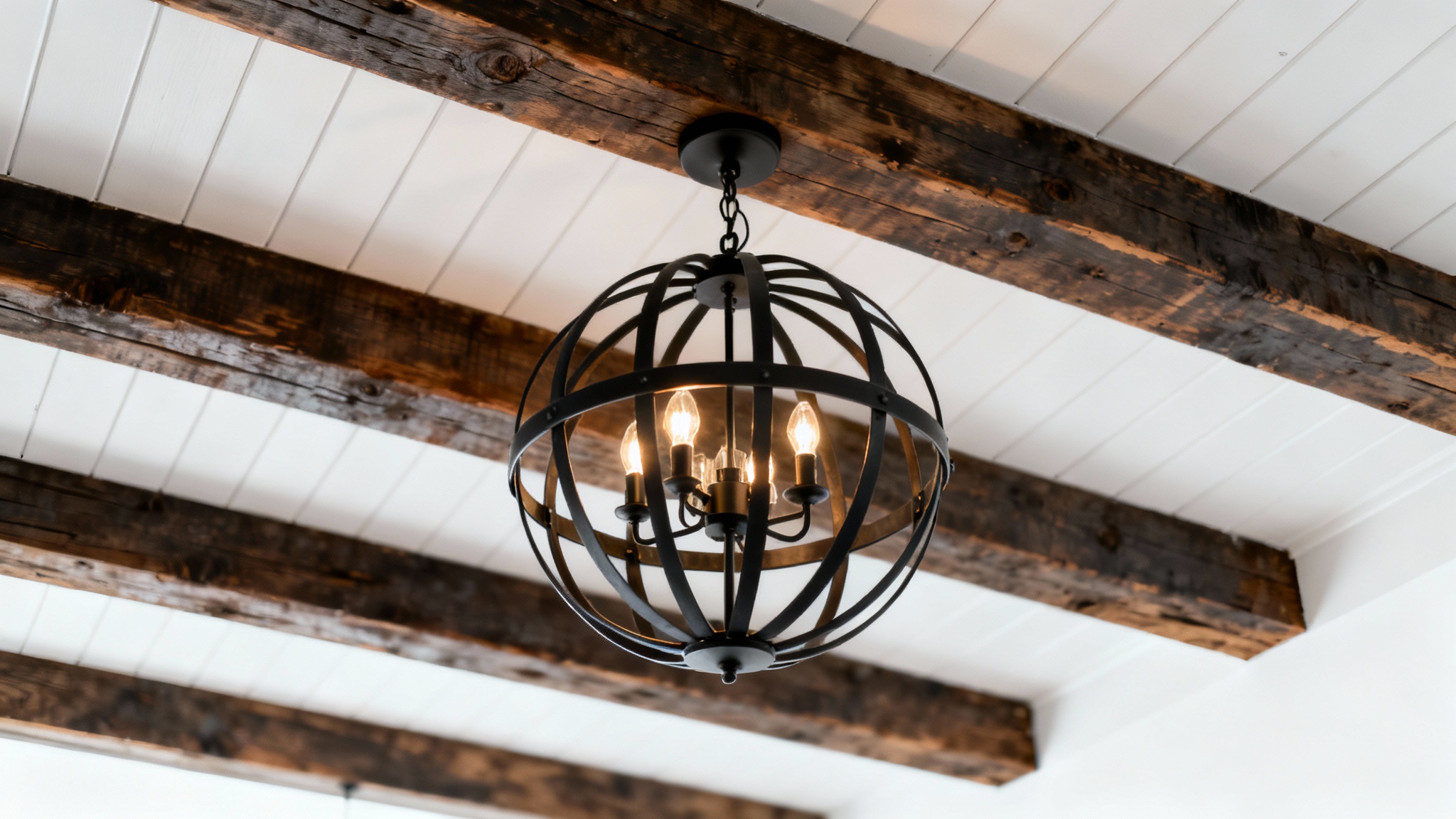 A mockup image of a modern farmhouse ceiling design featuring dark wooden beams, white shiplap, and a central black orb chandelier, all against a clean white background.
