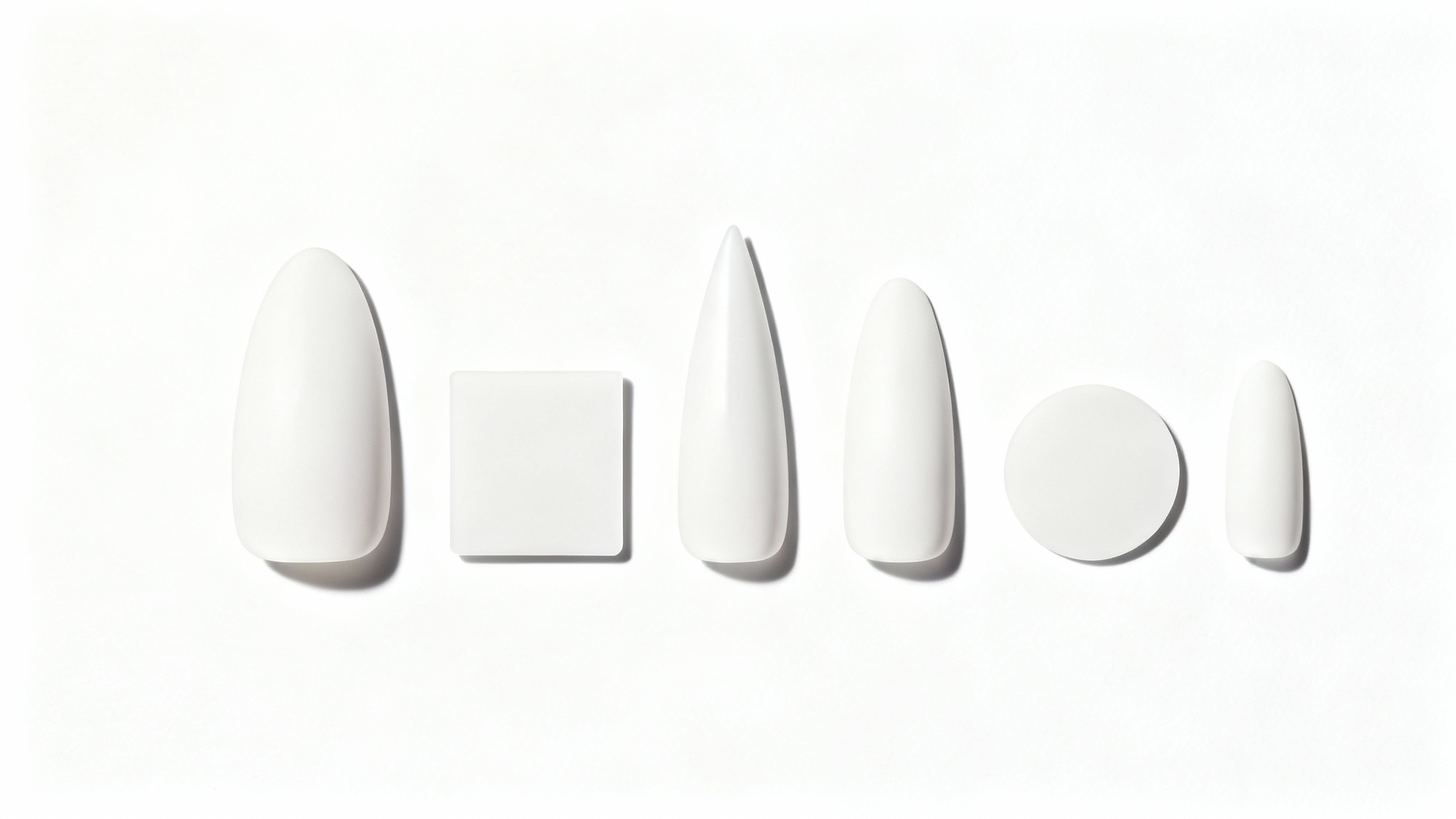 An organized row of artificial nail tips in various shapes, almond, square, coffin, stiletto, round, and oval, on a white background.
