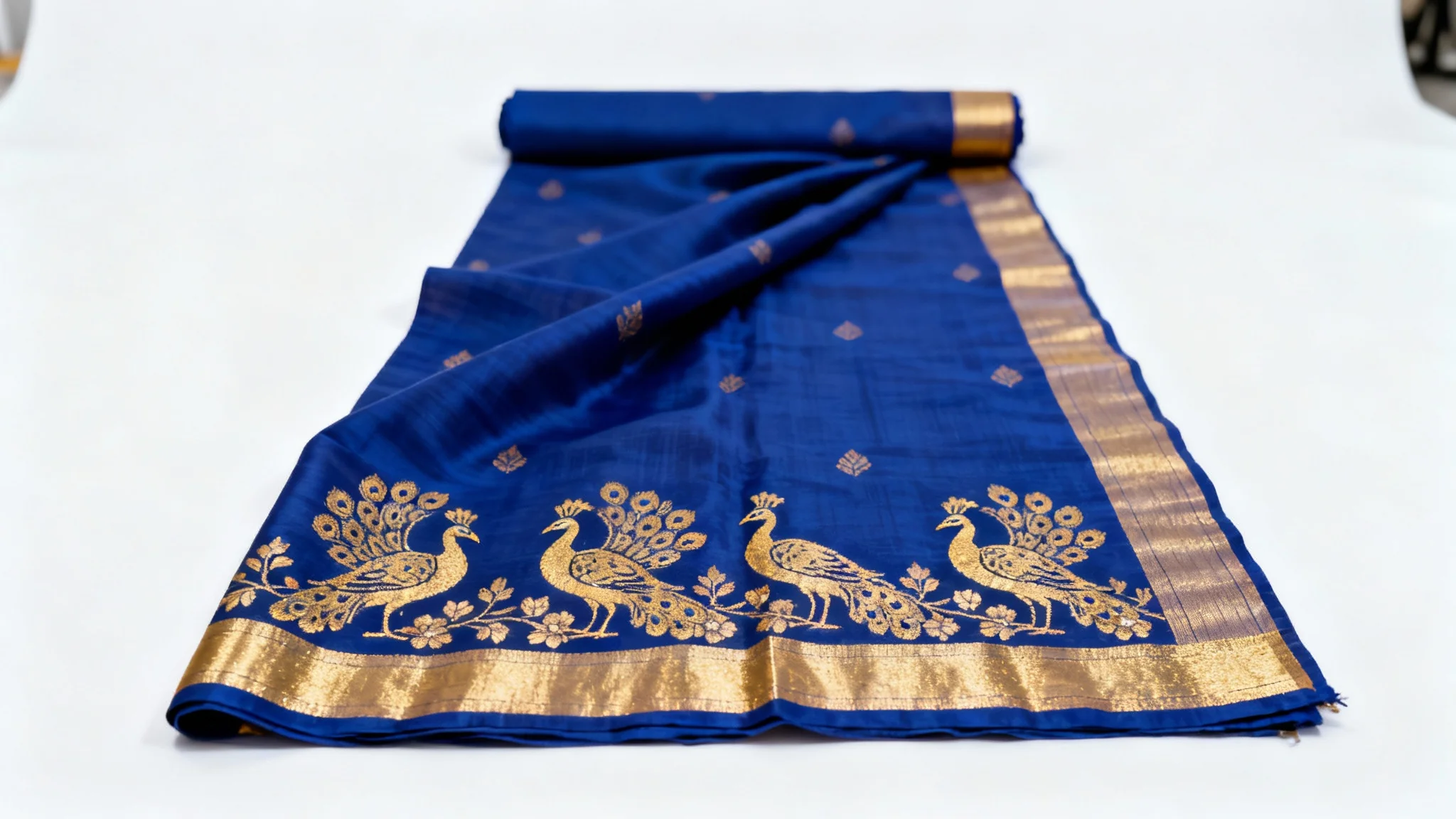 A luxurious royal blue and gold silk saree mockup, elegantly draped to showcase its intricate peacock and floral embroidery against a plain white background.