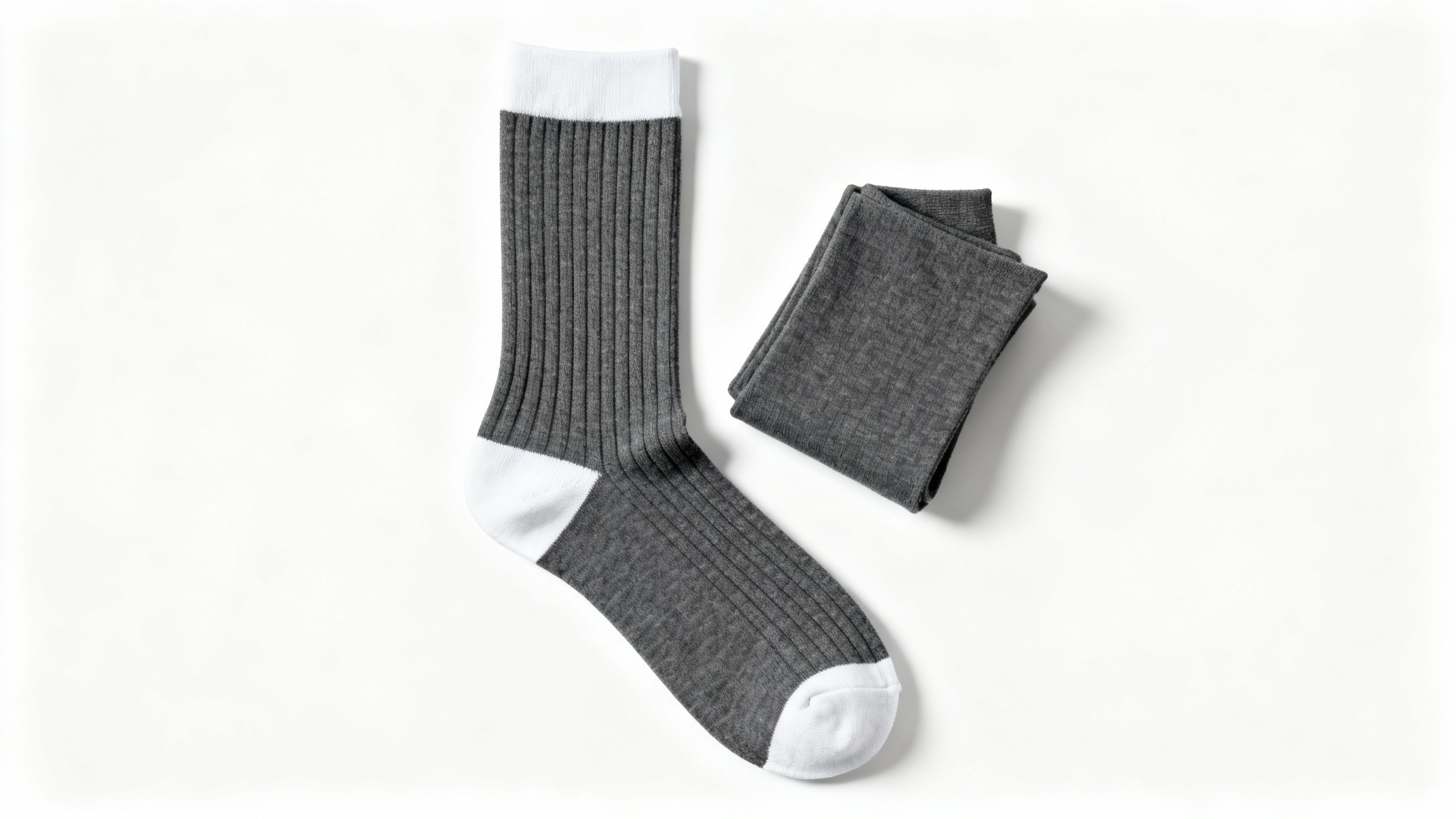 A product mockup of a pair of charcoal grey crew socks with white accents, one laid flat and the other folded, on a pristine white background.