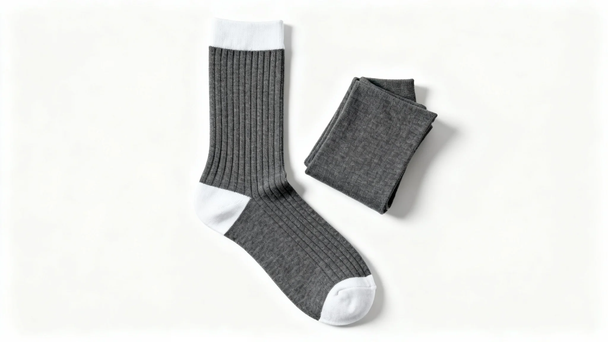 A product mockup of a pair of charcoal grey crew socks with white accents, one laid flat and the other folded, on a pristine white background.