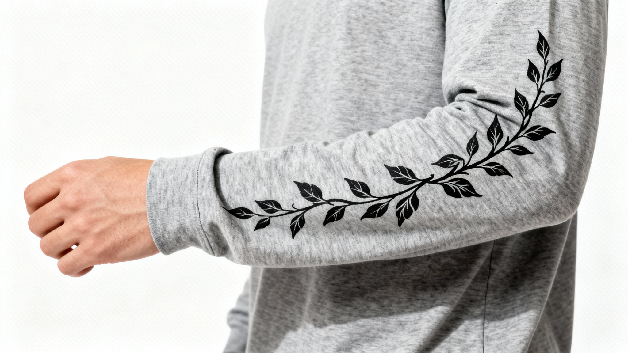 A close-up product mockup of a heather grey long-sleeve shirt, showcasing a detailed black floral vine design printed down the sleeve, set against a clean white background.
