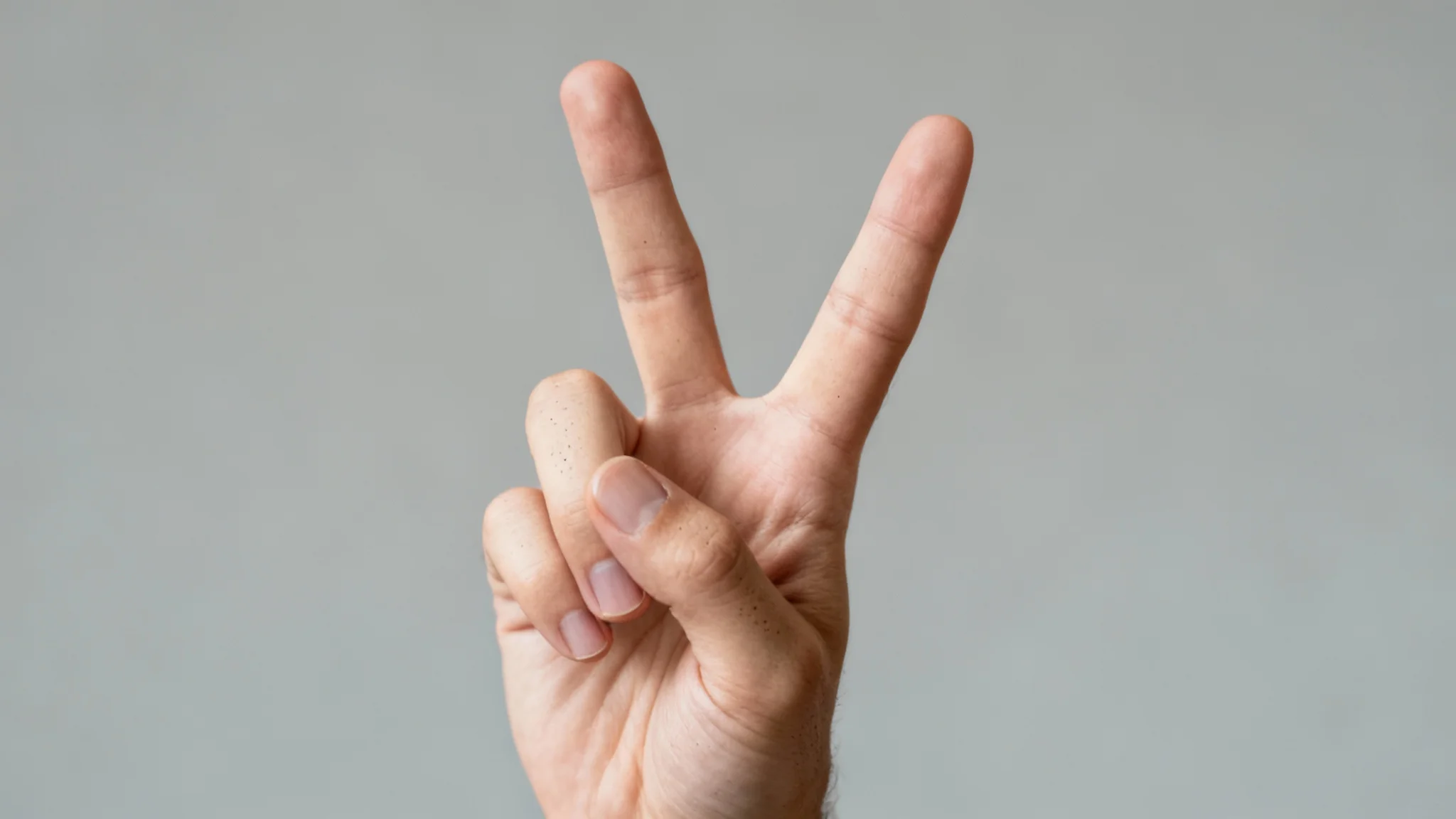 An extremely realistic, close-up photo of a hand making a peace sign, set against a clean, neutral gray background, highlighting the detailed skin texture.