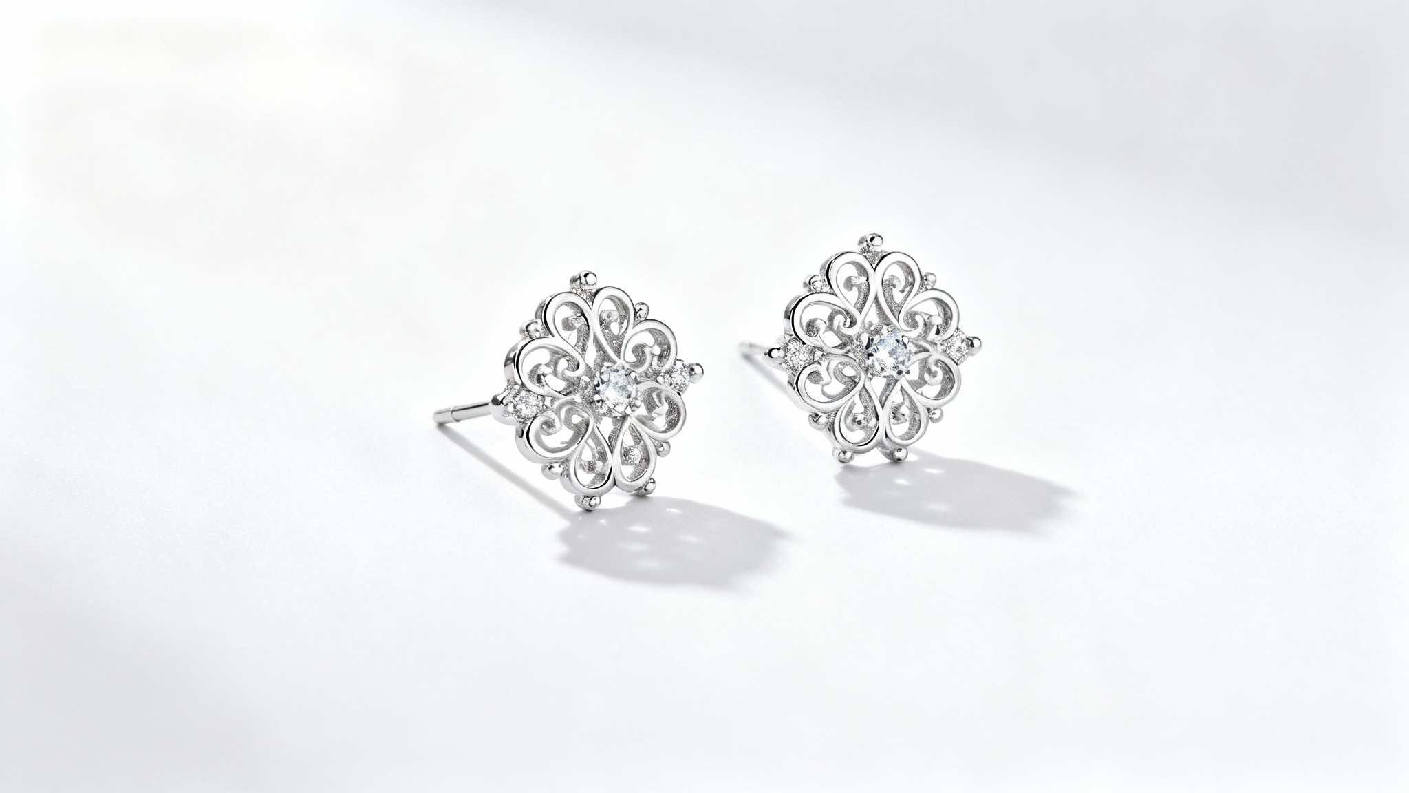 A professional jewelry photograph of elegant silver filigree earrings with small diamonds, shot in a studio with soft lighting on a clean white background.