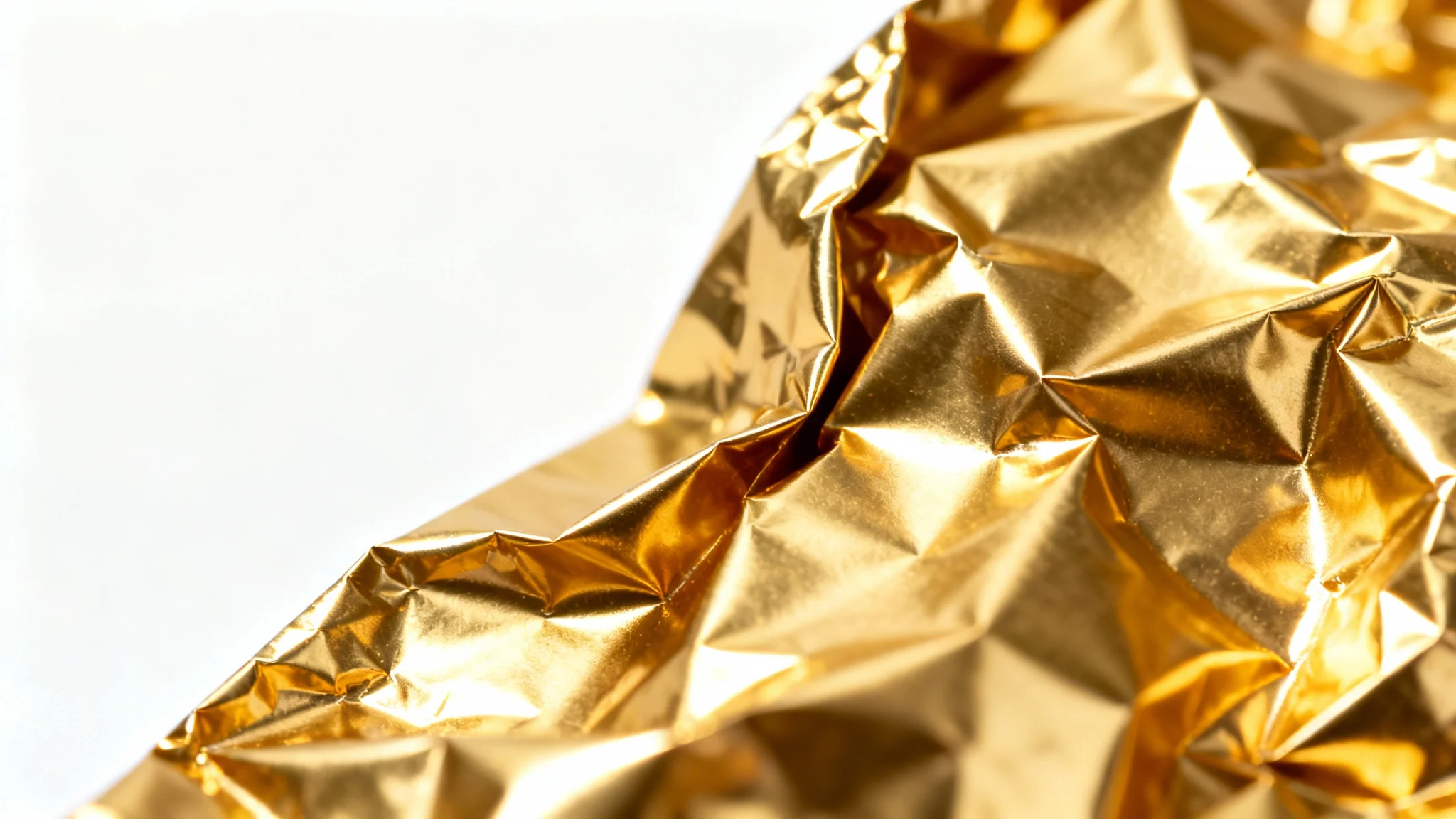 A photorealistic close-up of a crumpled gold foil texture on a clean white background, highlighting its luxurious metallic sheen and intricate creases.