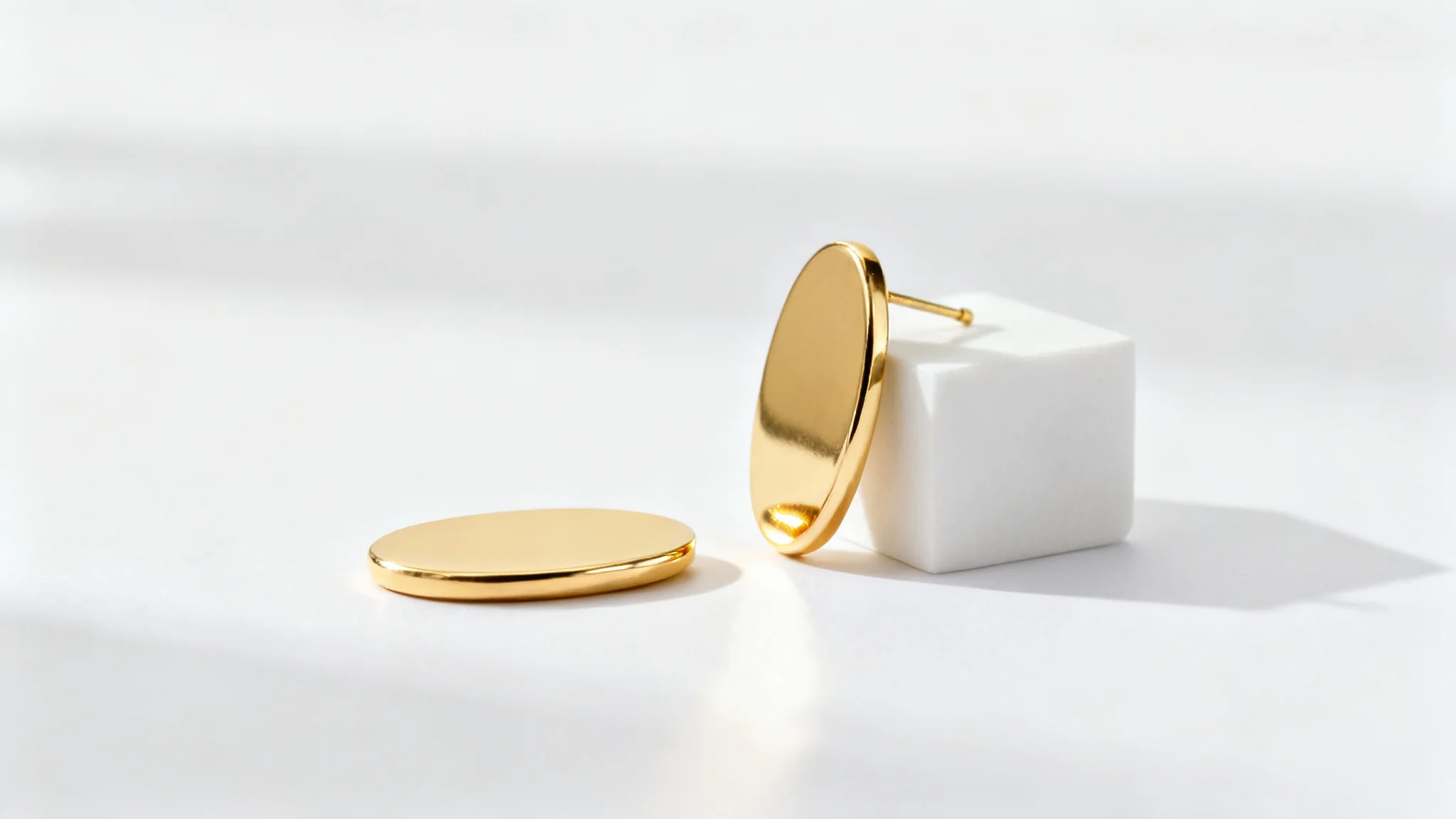 A professional studio shot of a pair of minimalist gold earrings artfully arranged on a clean white background, showcasing a luxurious and modern aesthetic.