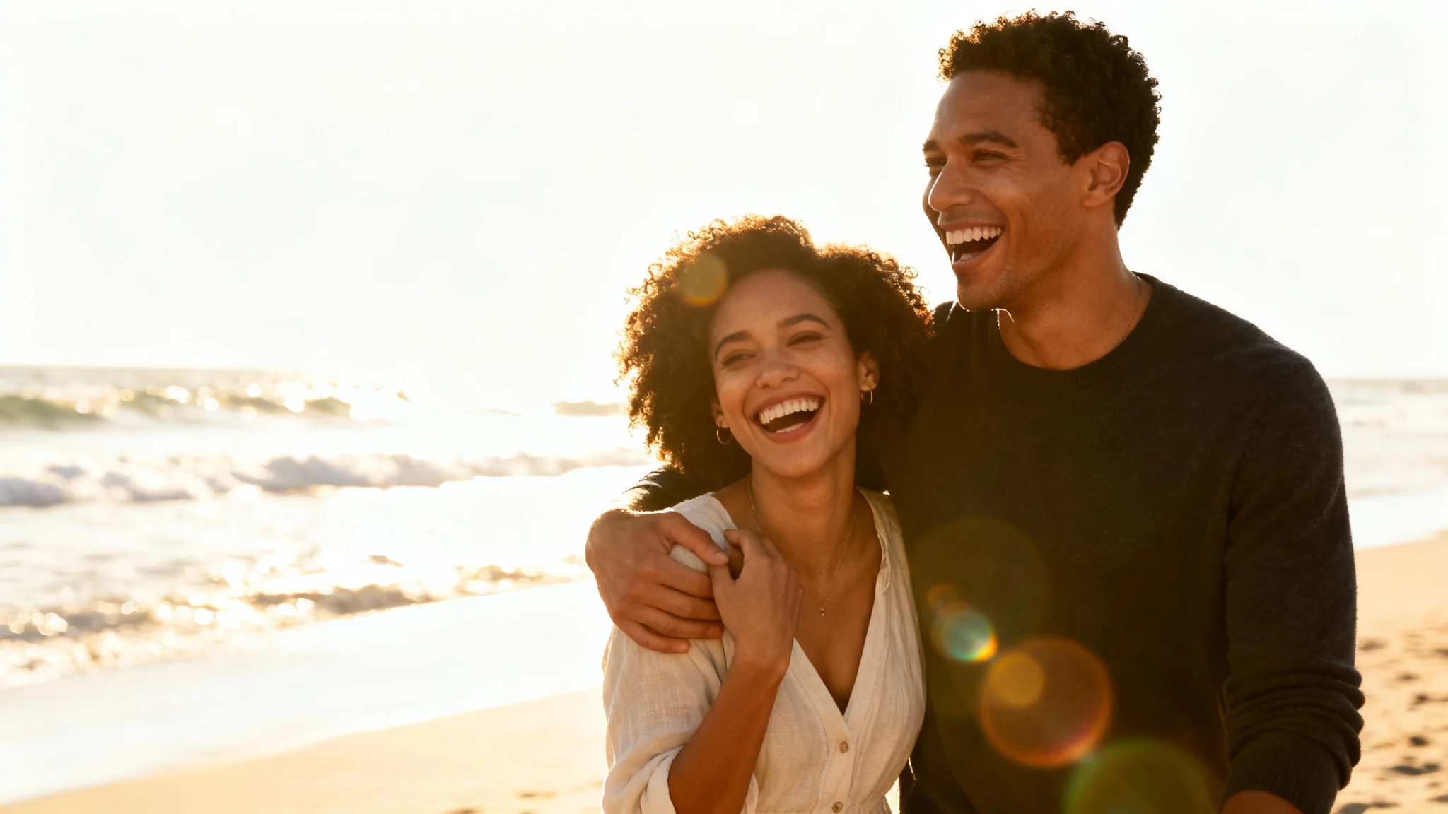 A professionally edited photograph of a young, happy couple laughing together on a beach at sunset, showcasing a perfect, romantic moment.