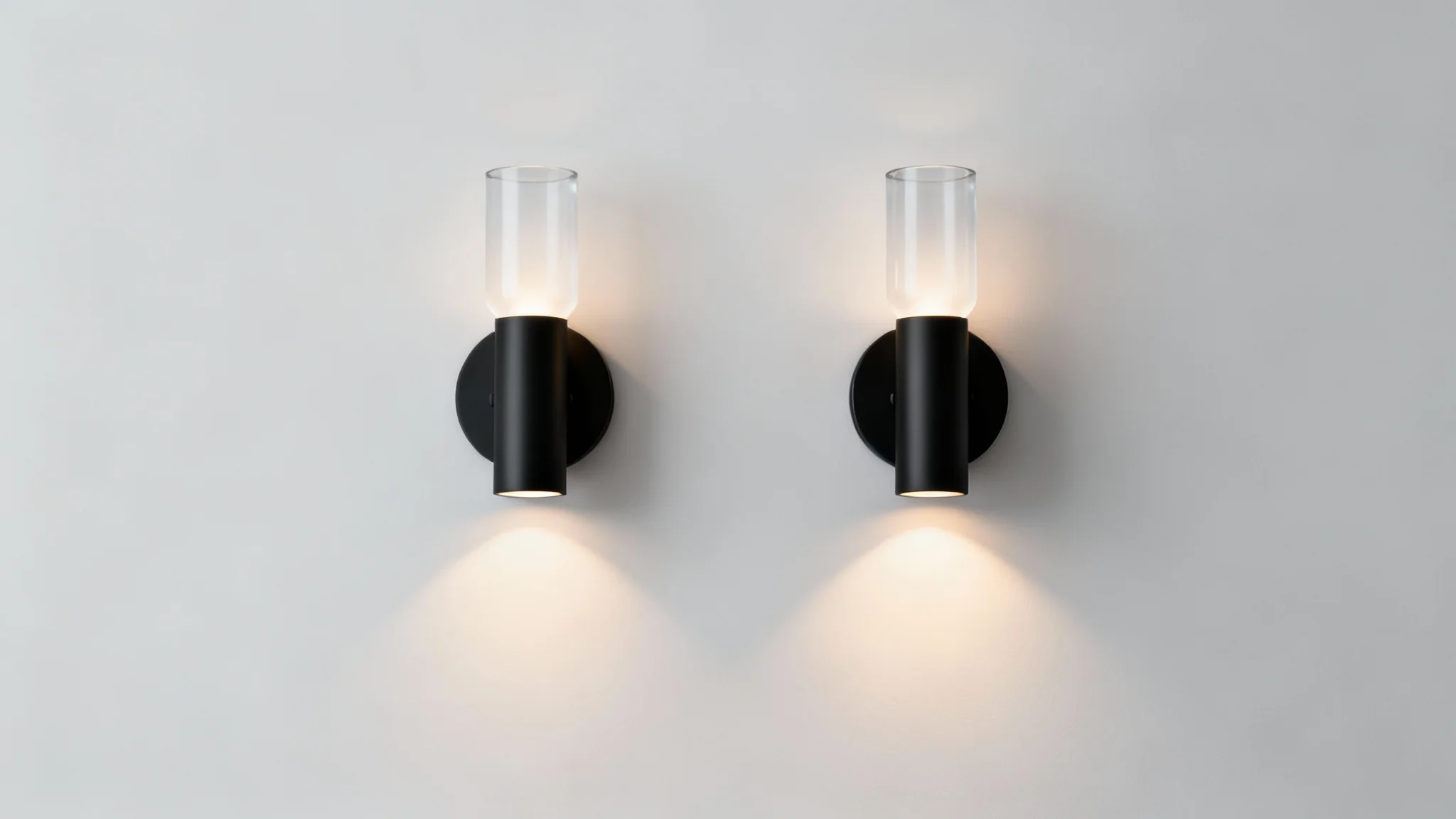 A pair of modern, matte black cylindrical wall sconces mounted symmetrically on a wall, presented as a clean product mockup against a light gray background.