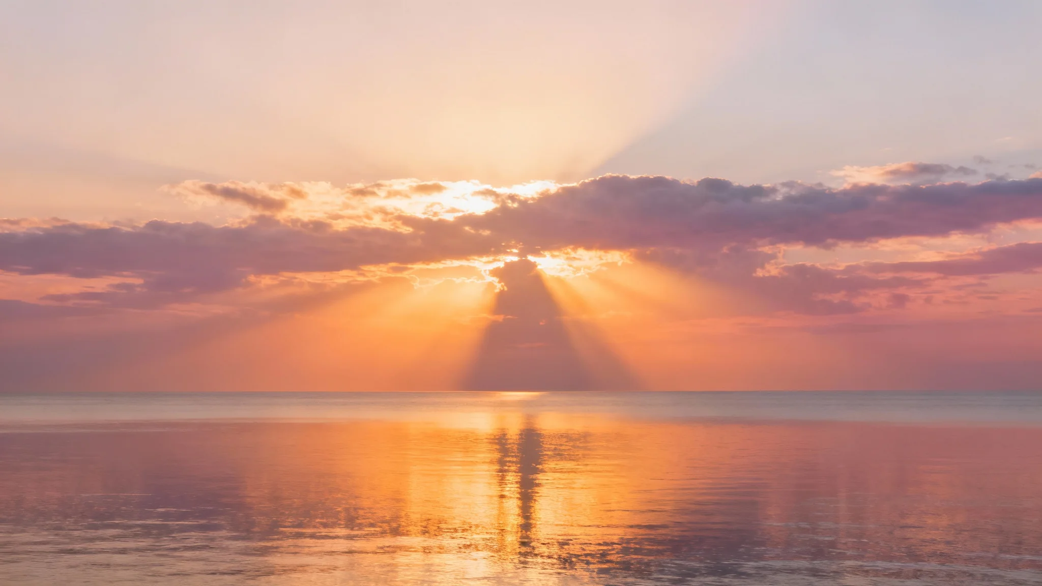 A serene and majestic sunrise over a calm ocean, with golden rays of light breaking through the clouds, creating a peaceful and spiritual atmosphere suitable for a bible verse background.
