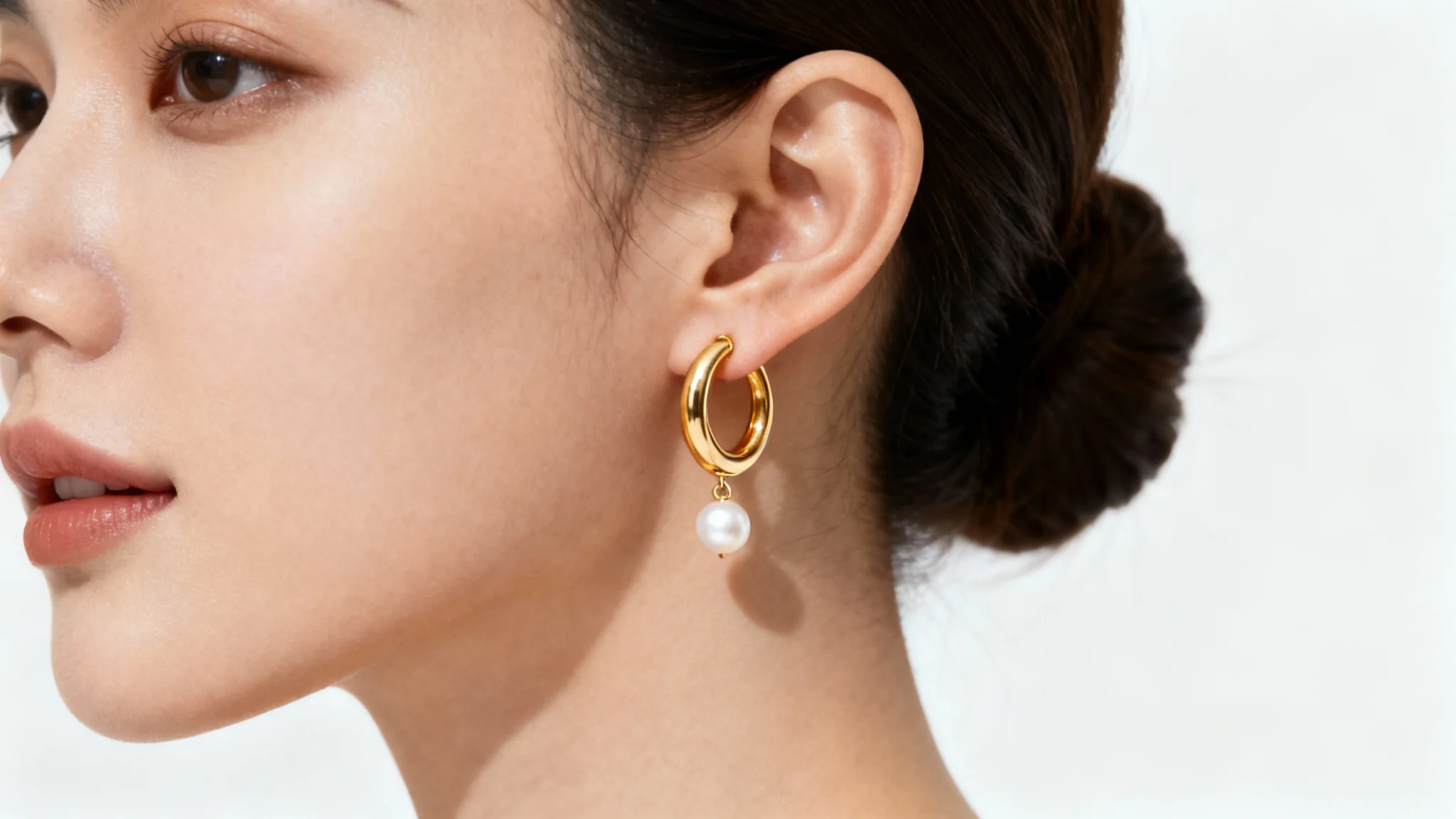 A hyperrealistic close-up of a woman's ear showcasing a virtual try-on of a delicate gold hoop and pearl earring against a plain white background.