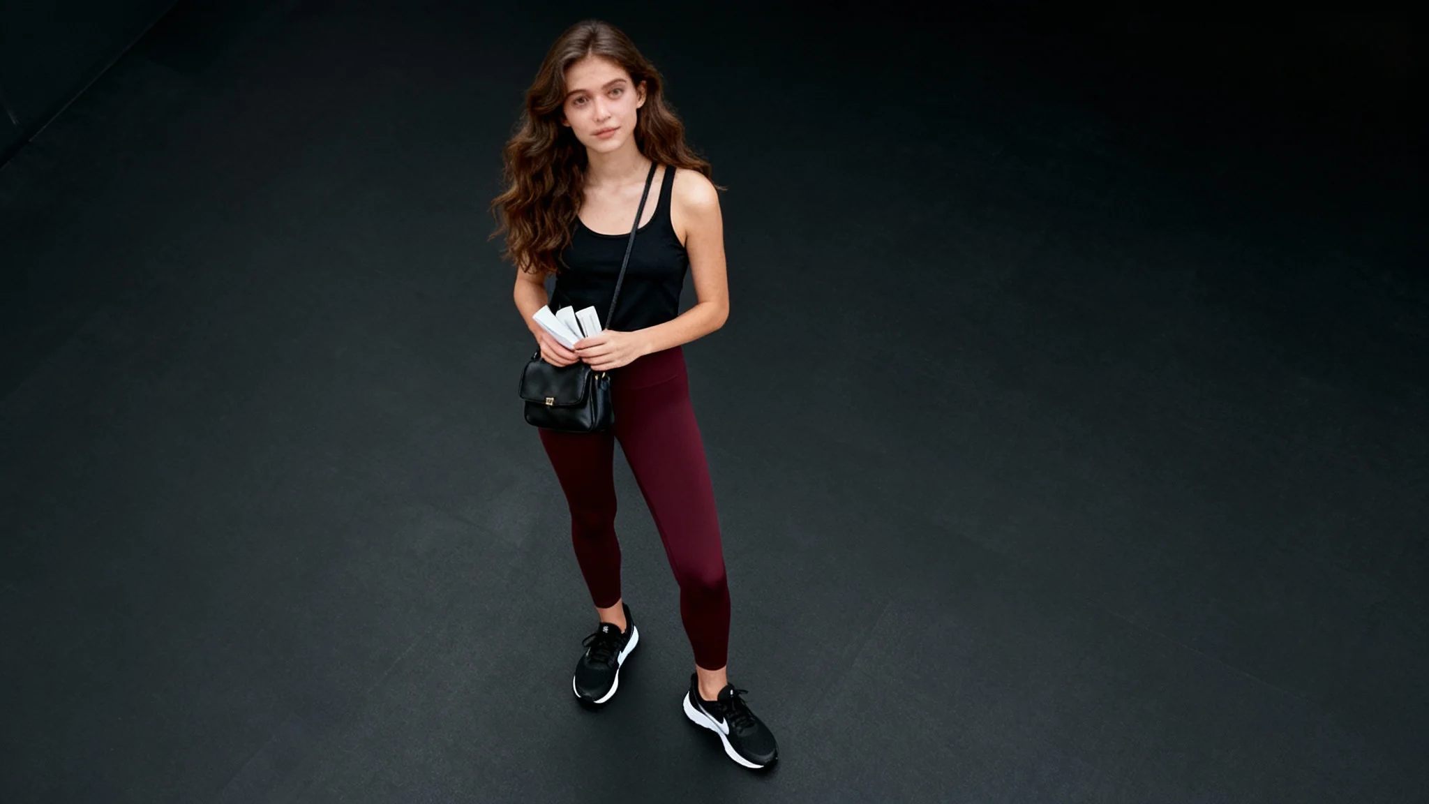 A bird's-eye view photograph showing the final result of a perspective change tool. A woman in athletic wear is on a black background, looking up at the camera from directly above, demonstrating a dramatic change from a low-angle shot.