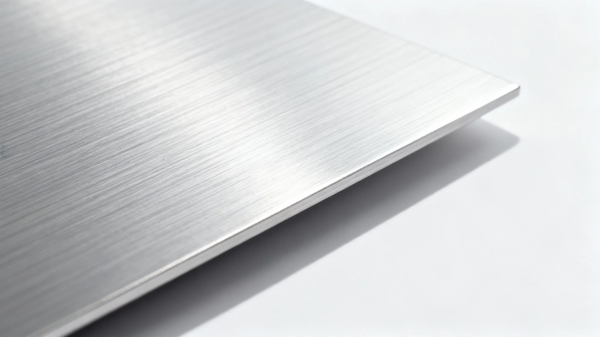 A close-up, high-resolution image of a brushed aluminum surface, with fine horizontal lines and a metallic silver sheen under soft lighting against a white background.