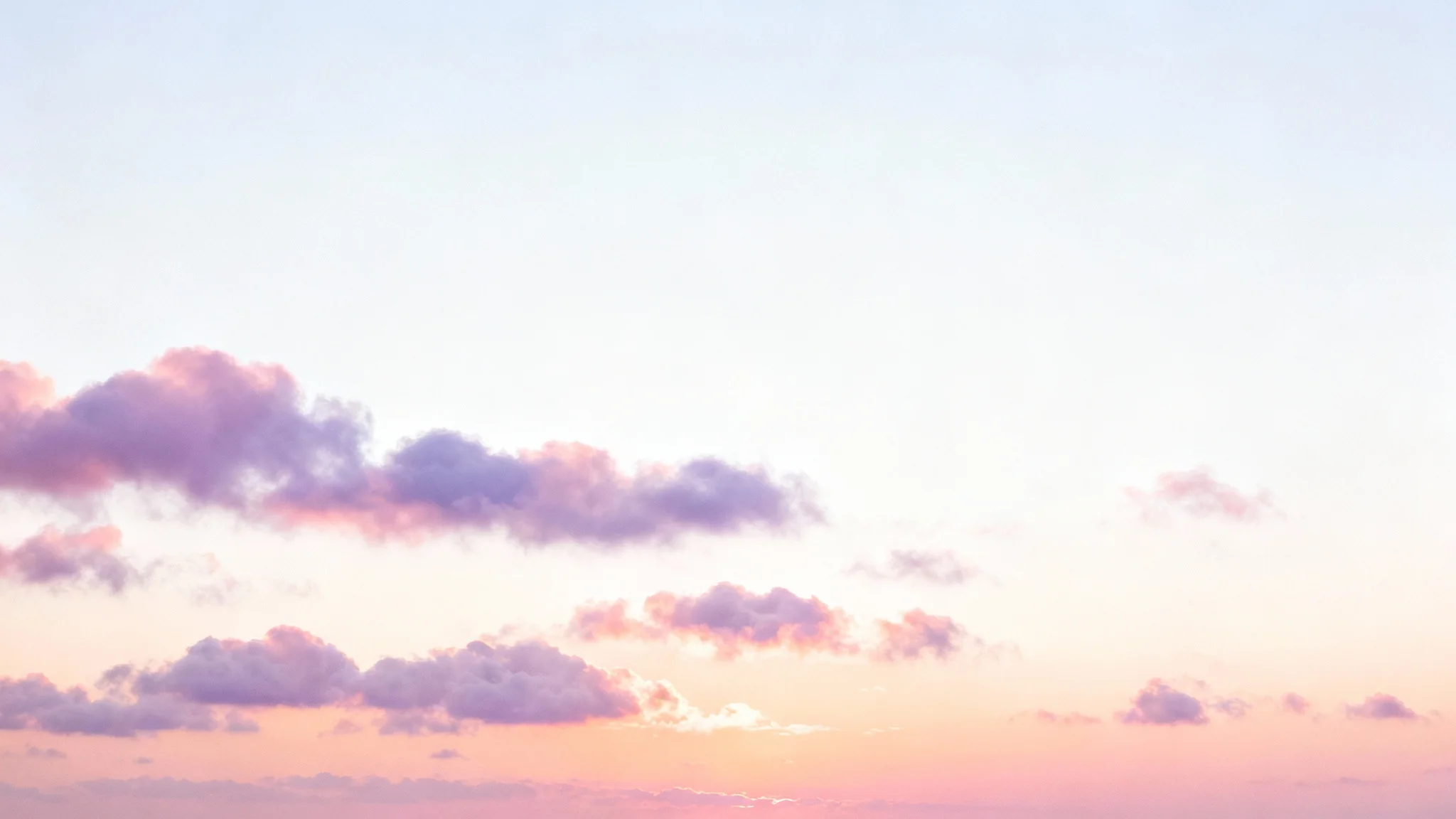 A dreamy and serene pastel sky with fluffy clouds, featuring a soft color gradient of pink, lavender, and blue, perfect for a background.