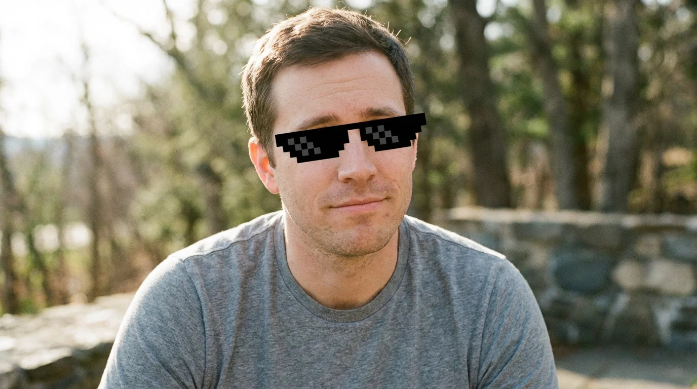 A photo of a man smirking while wearing black pixelated 'deal with it' sunglasses.