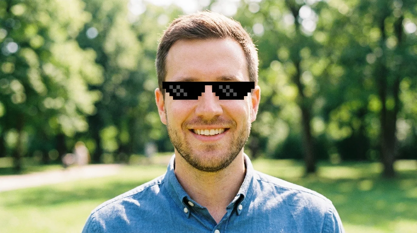 A man smiling in an outdoor park setting, with pixelated black 'deal with it' sunglasses edited onto his face.