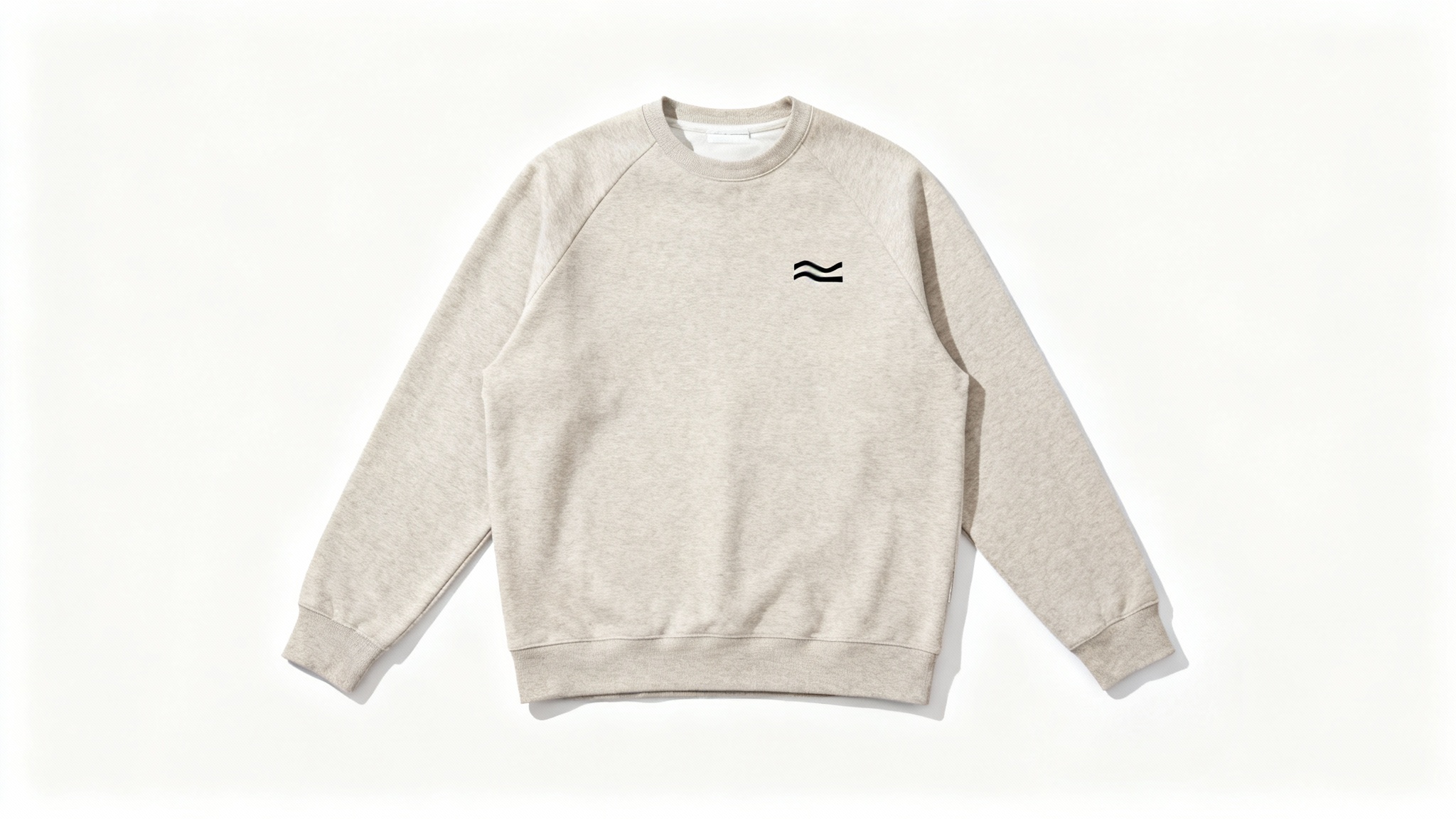 A flat lay photograph of a minimalist, high-quality sweatshirt in a neutral color on a clean white background, featuring a small, simple graphic design on the chest.