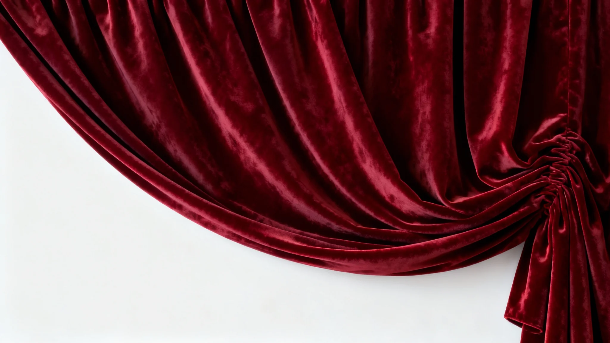 A close-up shot of a luxurious red velvet curtain with deep, soft folds, set against a plain white background, highlighting its rich texture and color.