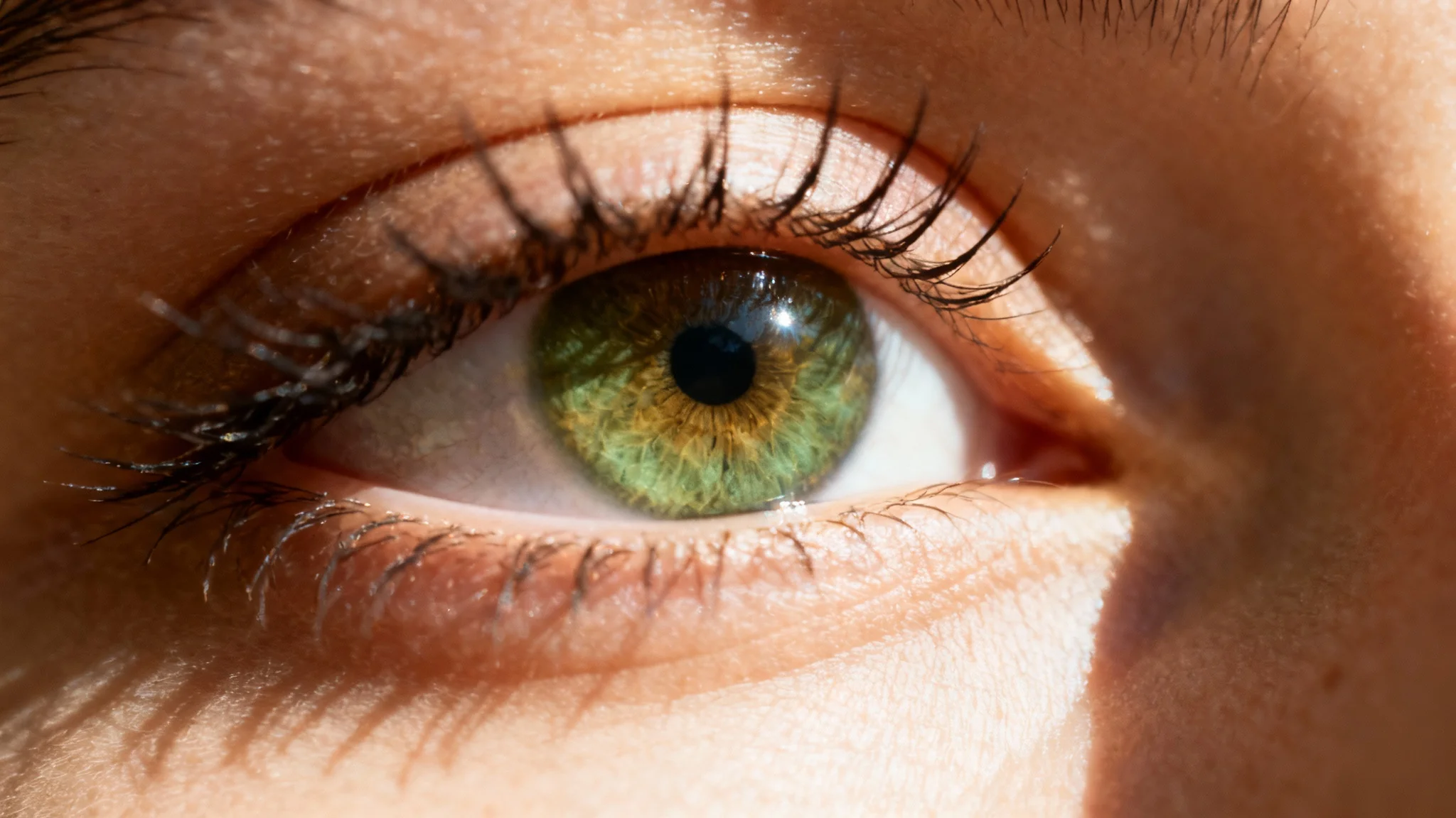 A close-up macro photograph of a beautiful human eye opening, symbolizing an awakening or transition. The image is set against a stark white background.