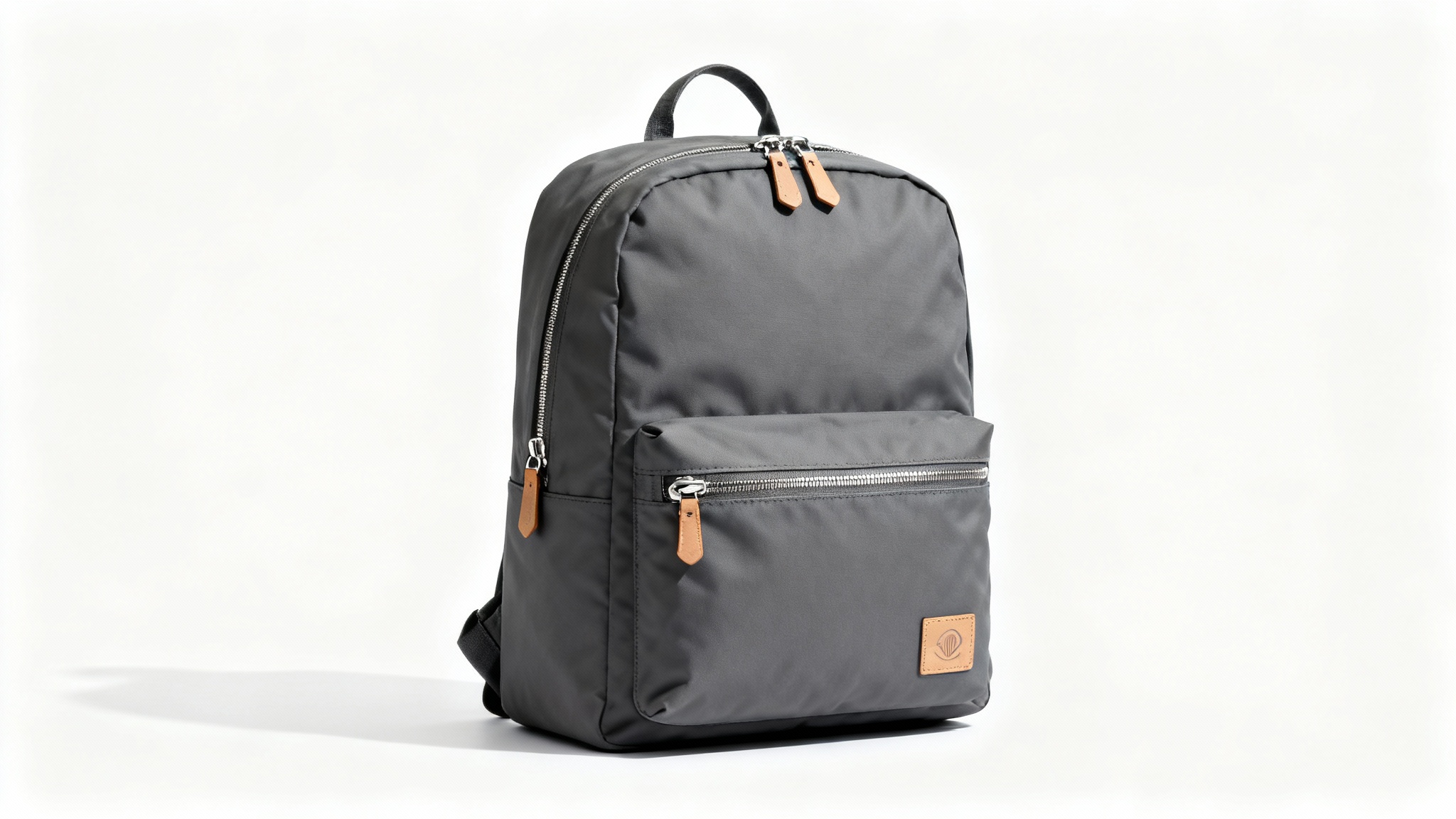 A modern charcoal grey backpack with tan leather details, photographed professionally against a clean white background to highlight its minimalist design.