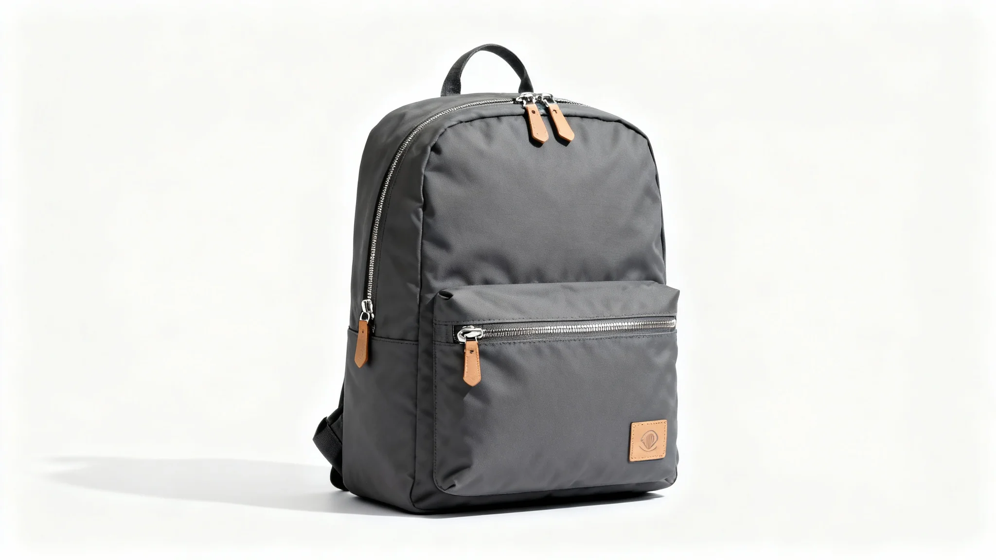 A modern charcoal grey backpack with tan leather details, photographed professionally against a clean white background to highlight its minimalist design.