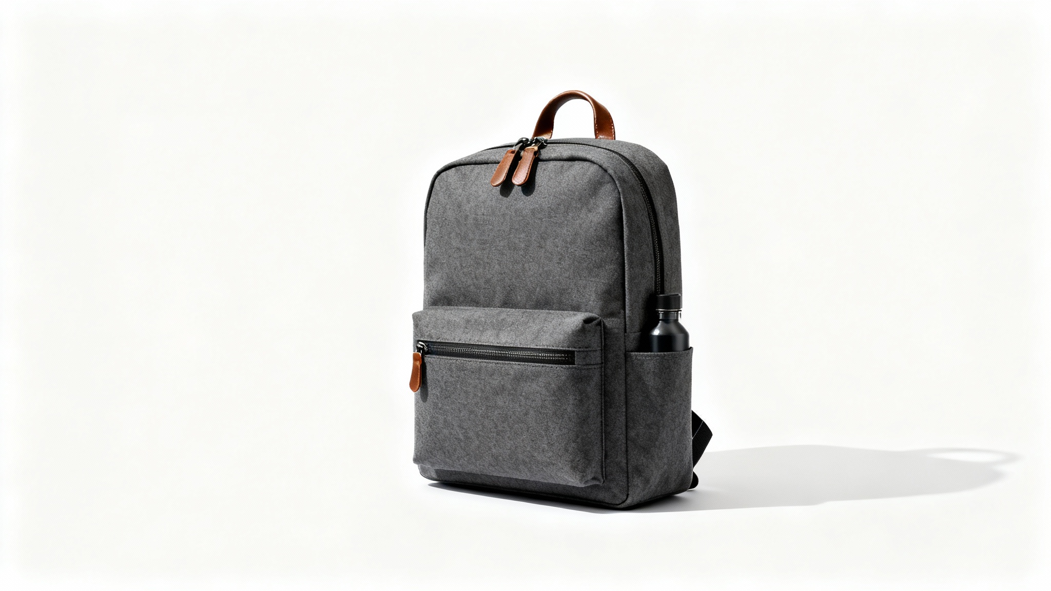 A modern, minimalist backpack in charcoal gray canvas with brown leather details, standing on a clean white background in a professional product shot.