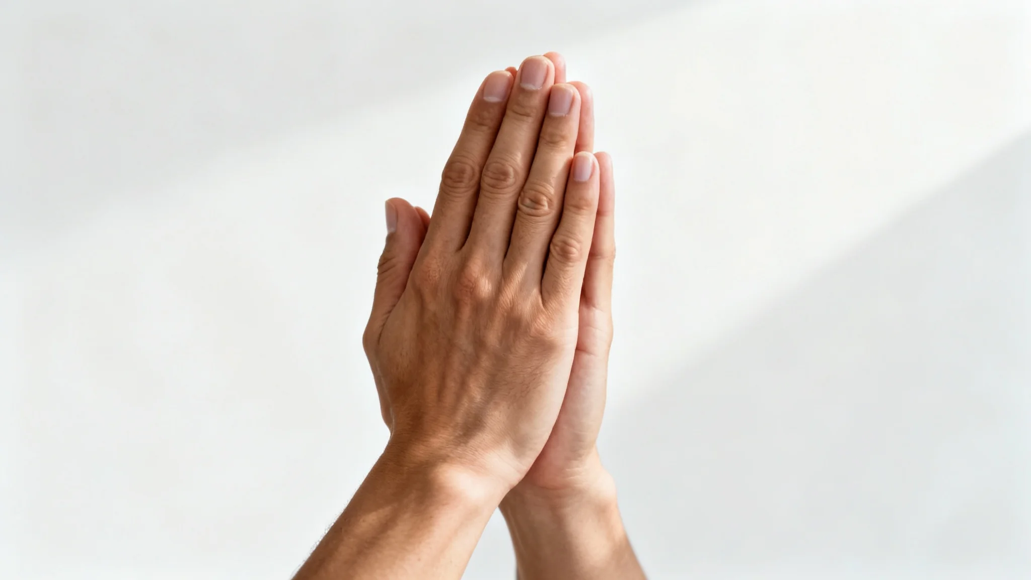 A photorealistic image of two hands clasped together in prayer, shown in close-up against a clean white background, creating a serene and spiritual feeling.