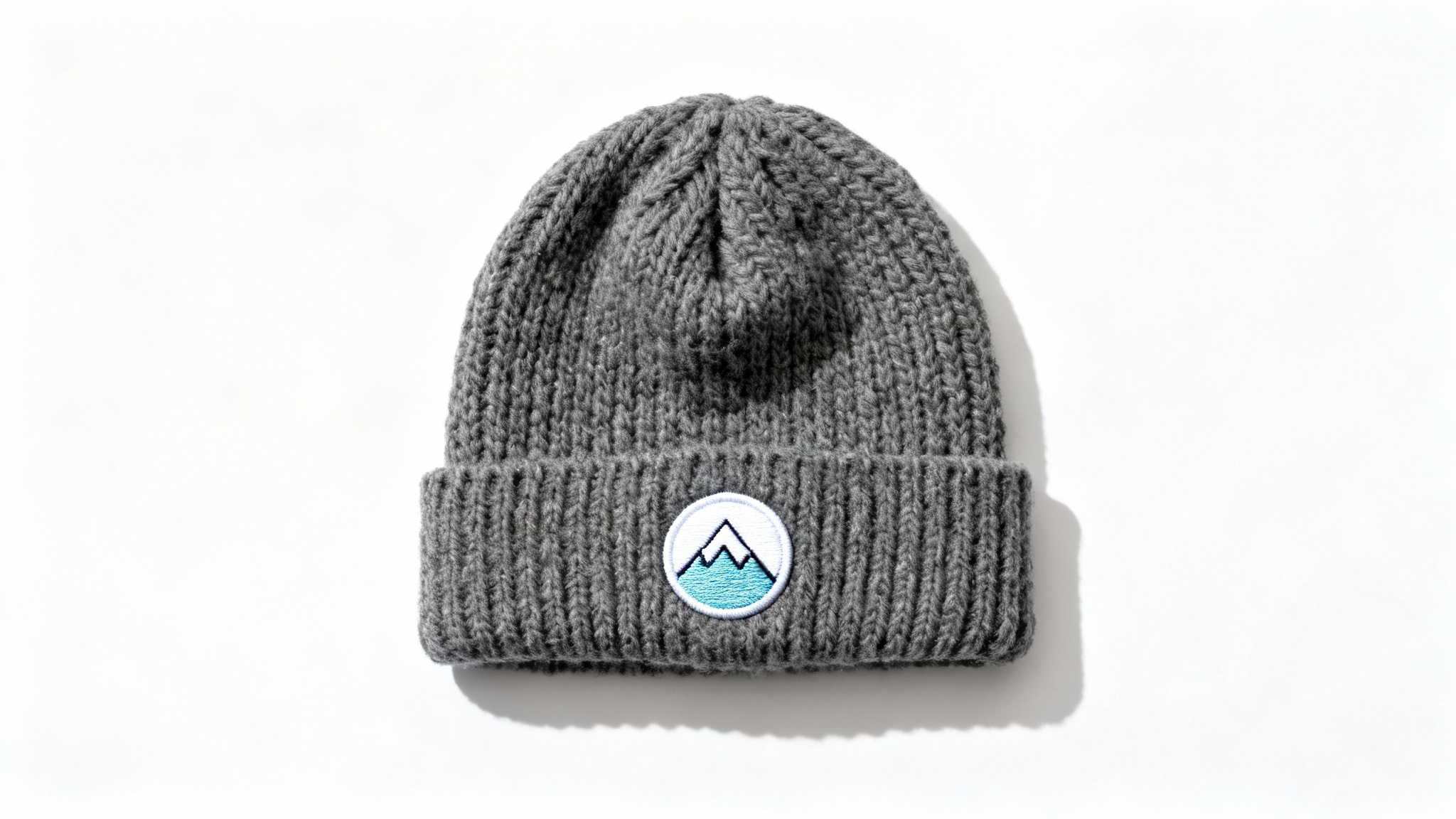 A product mockup of a custom charcoal gray knit beanie featuring a minimalist mountain peak logo embroidered on the cuff, set against a clean white background.