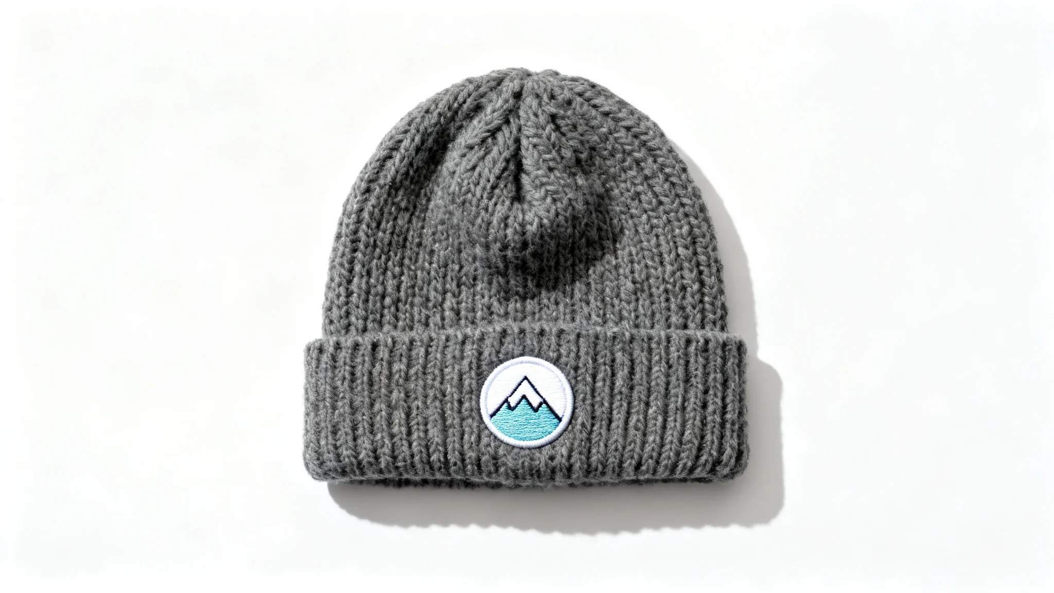 A product mockup of a custom charcoal gray knit beanie featuring a minimalist mountain peak logo embroidered on the cuff, set against a clean white background.