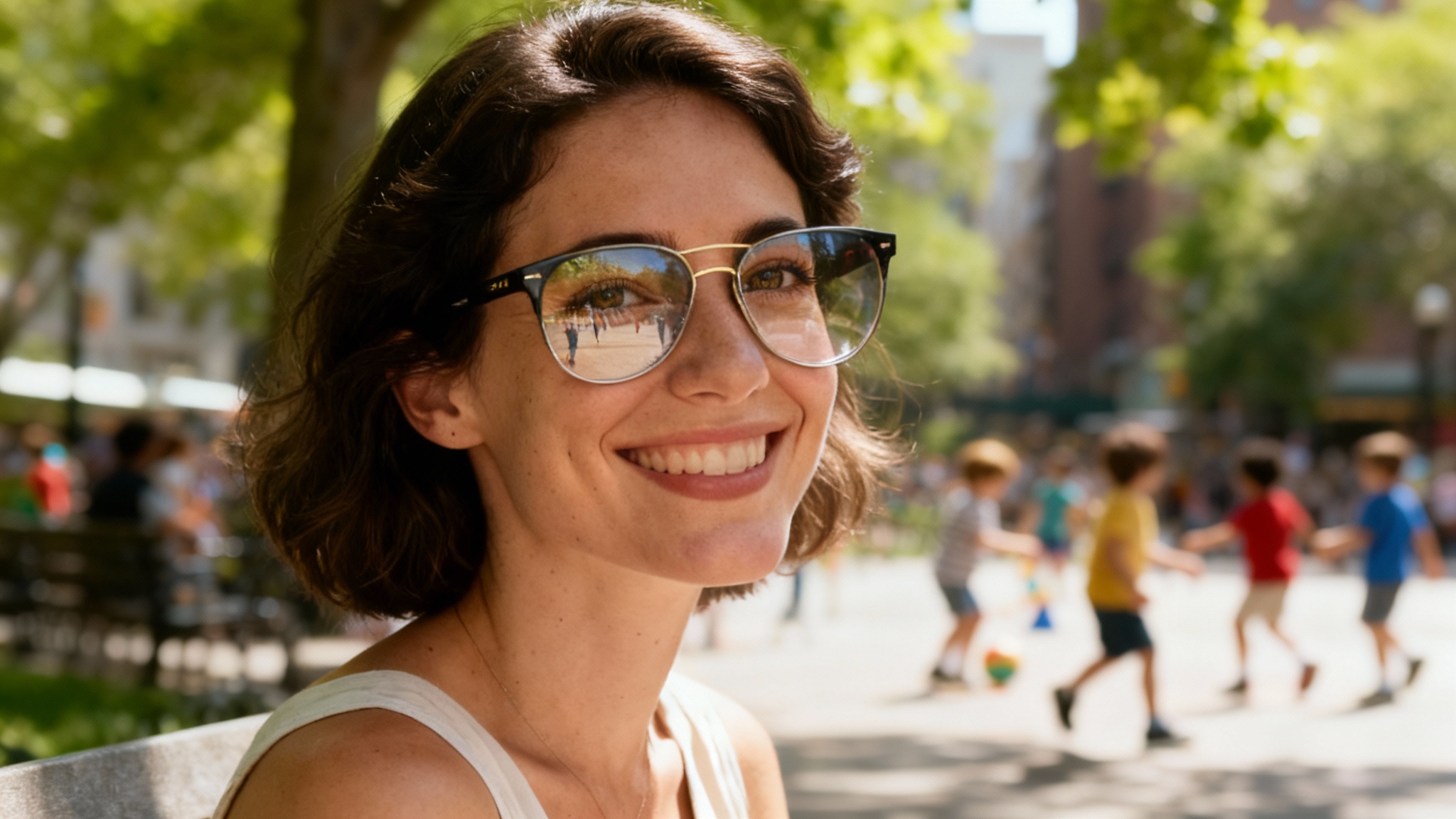 A professionally retouched photo of a woman in a park wearing sunglasses. Her eyes are clearly visible through the lenses with no reflections, and she is smiling warmly at the camera.