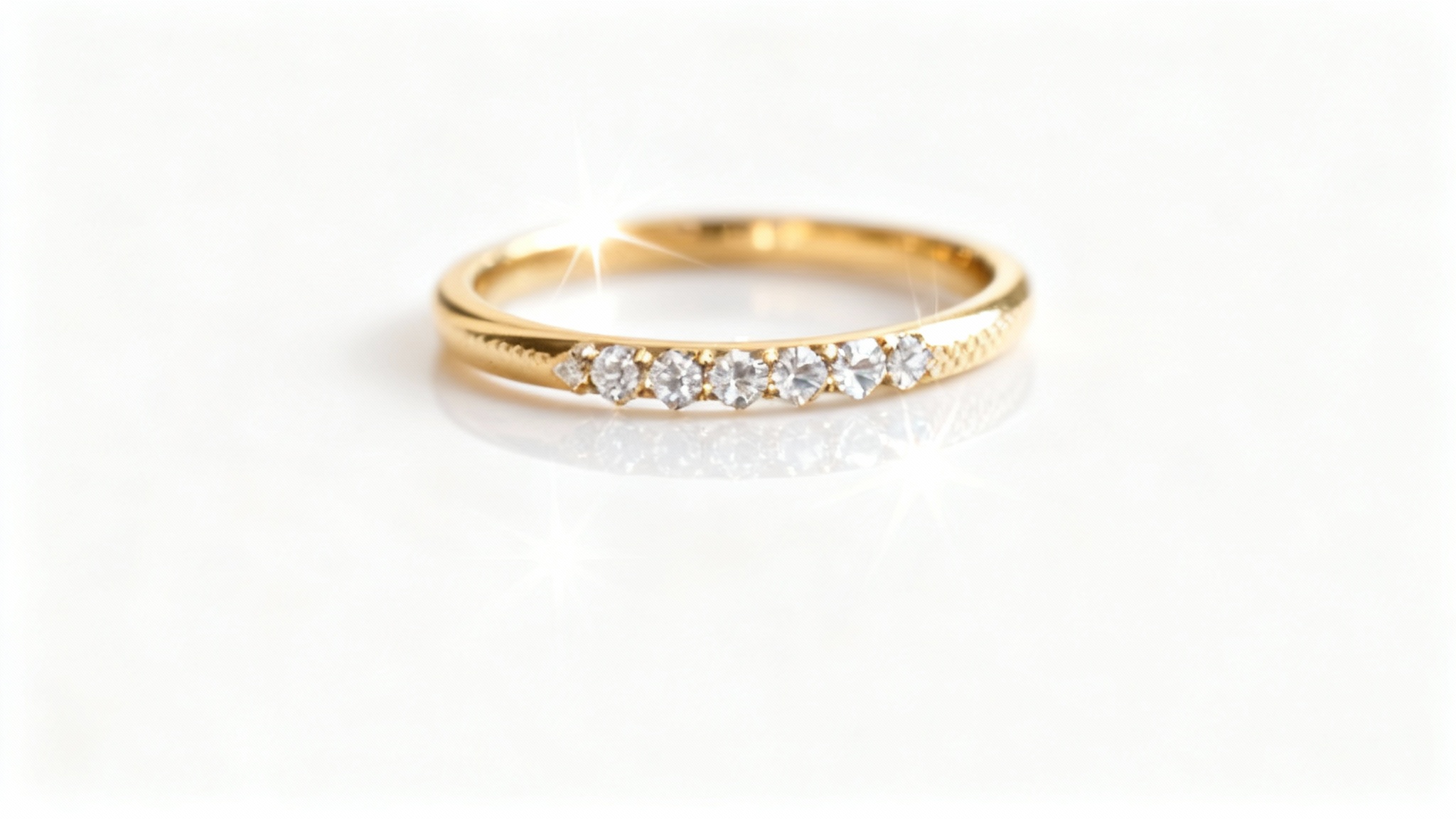 An ultra-detailed macro shot of a delicate gold ring with sparkling pavé diamonds, professionally lit against a pristine white background, highlighting its fine craftsmanship.