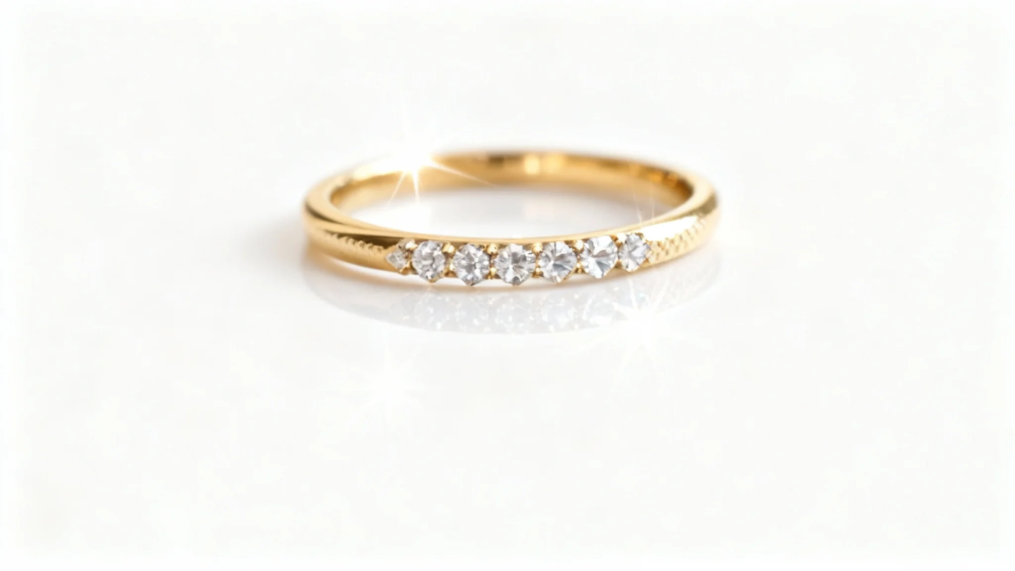 An ultra-detailed macro shot of a delicate gold ring with sparkling pavé diamonds, professionally lit against a pristine white background, highlighting its fine craftsmanship.