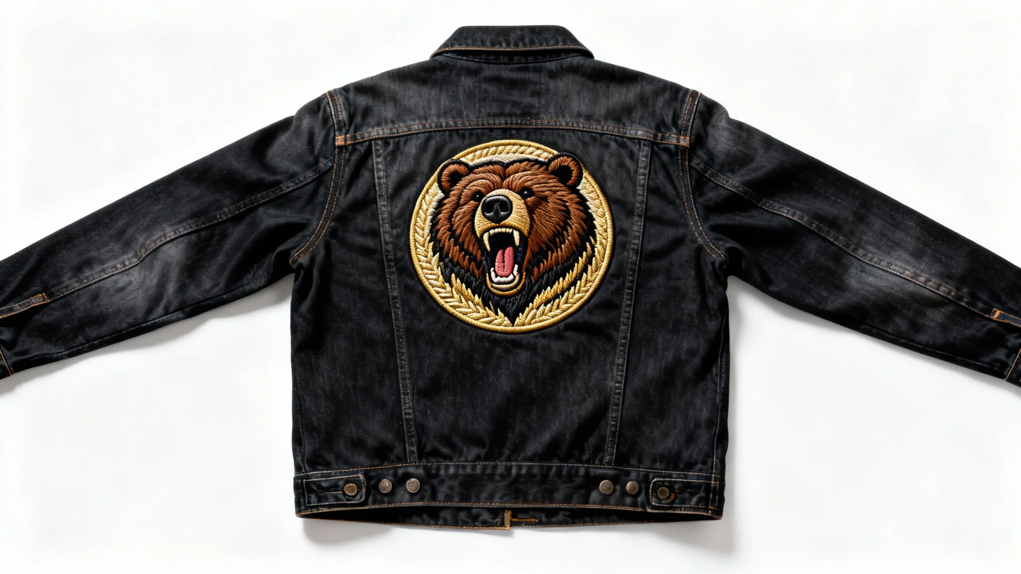A close-up of a dark denim jacket's back with a newly added, detailed embroidered patch of a roaring grizzly bear, showcased on a white background.