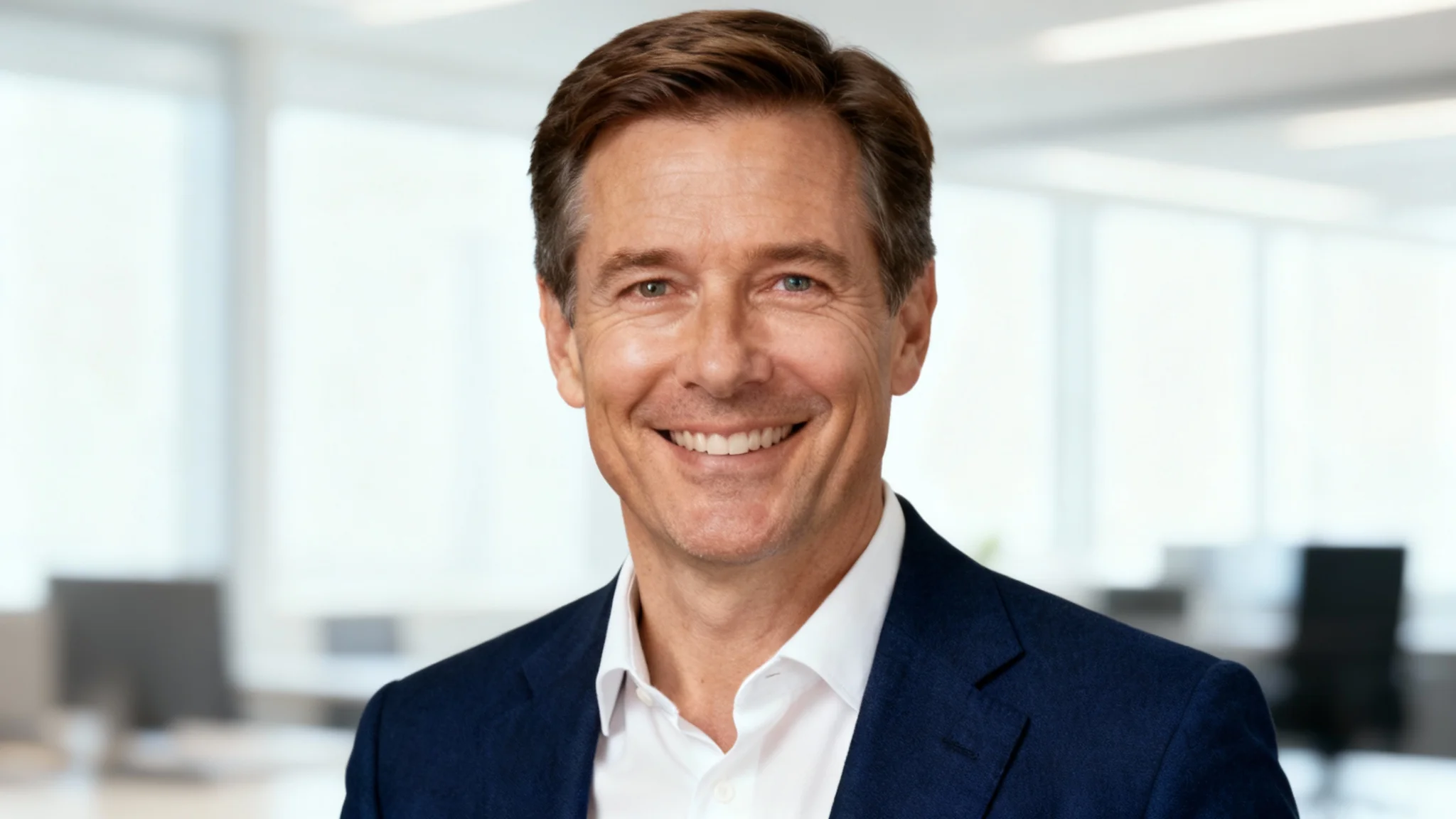 The final result of using the headshot tool: a hyper-realistic, professionally polished headshot of a middle-aged man in a suit against a blurred office background.