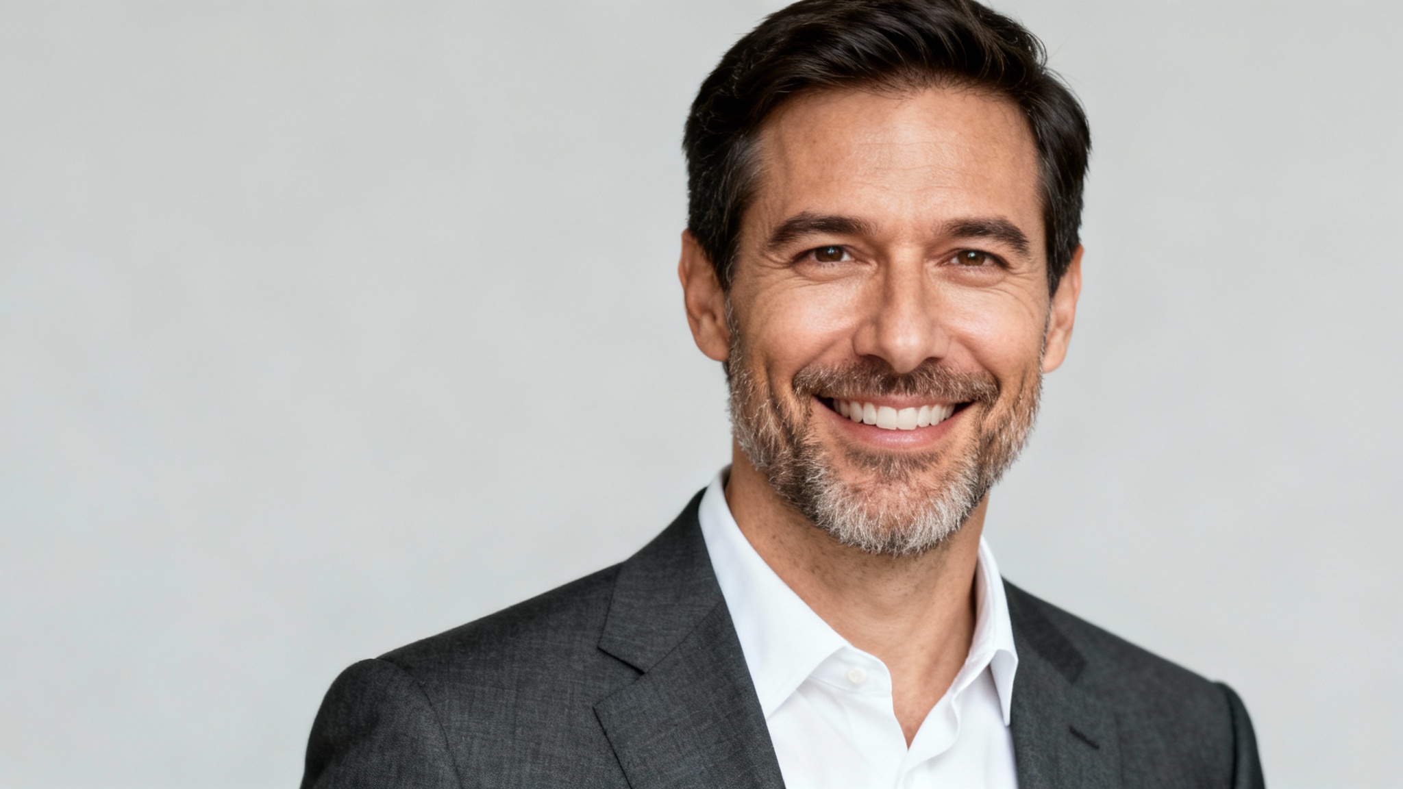 A hyper-realistic professional headshot of a smiling man in a suit against a plain light grey background, representing an AI-generated corporate portrait.