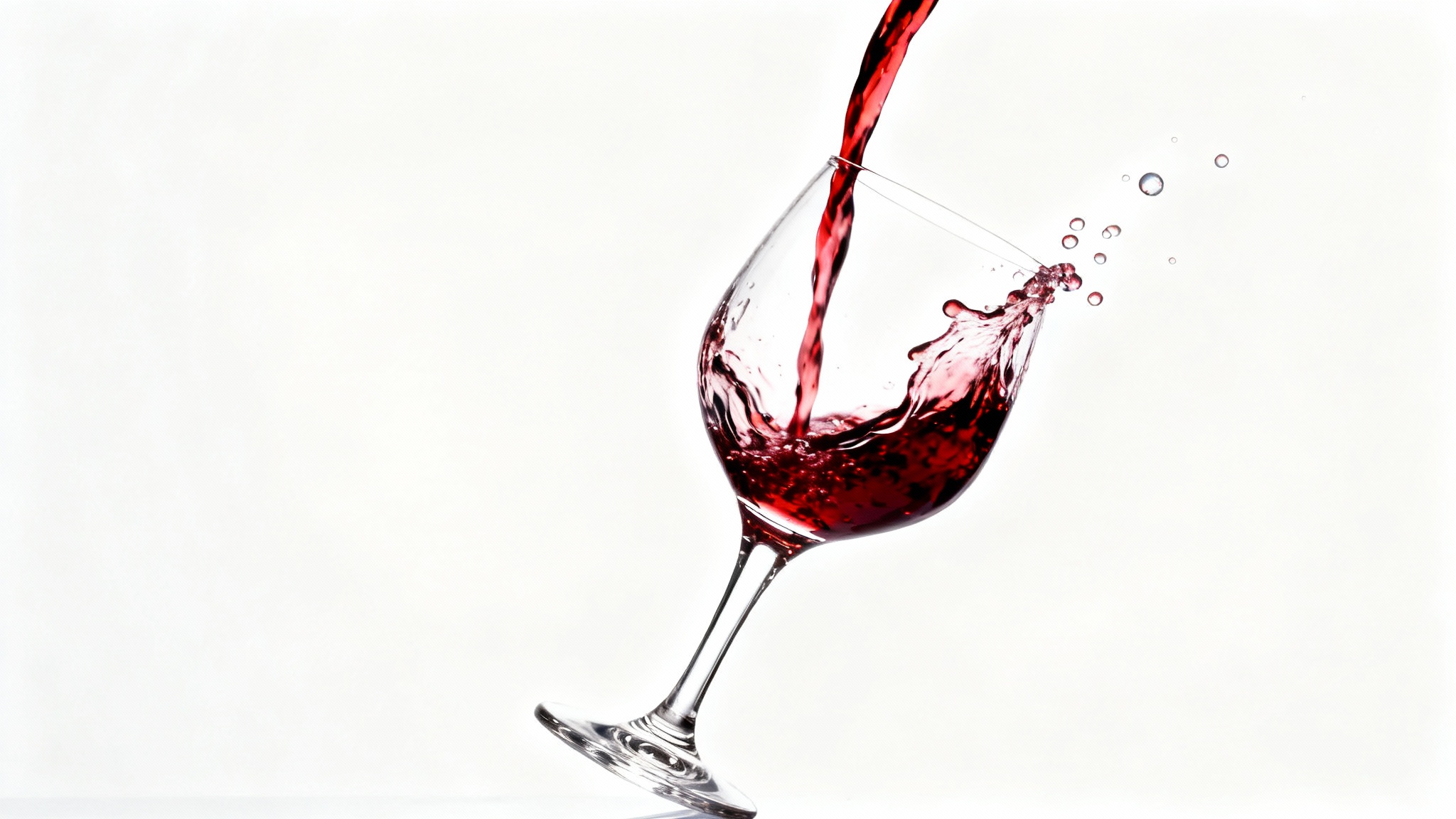 A photorealistic, high-speed shot of red wine being poured into a crystal glass, capturing the splash in mid-air against a clean white background.