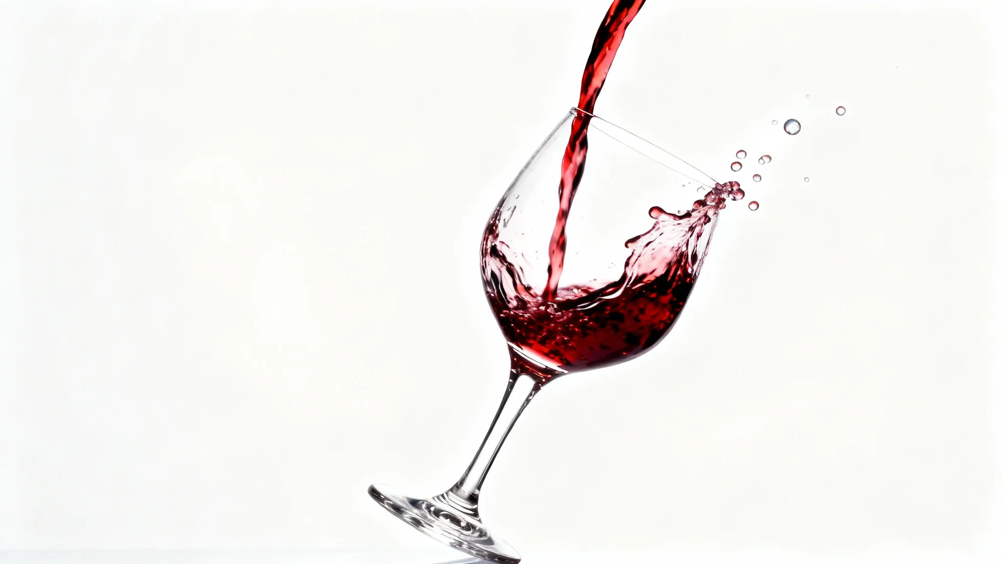 A photorealistic, high-speed shot of red wine being poured into a crystal glass, capturing the splash in mid-air against a clean white background.