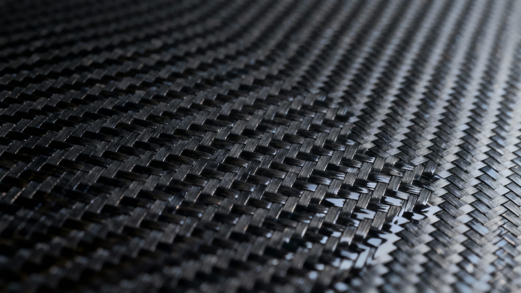 A close-up, high-resolution image of a sleek, glossy carbon fiber texture, showing the intricate diagonal weave pattern reflecting light on its dark, modern surface.