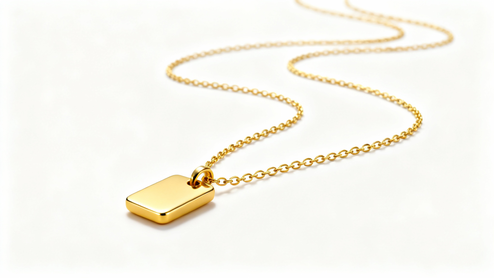 A professional product photograph of an elegant, minimalist gold necklace with a delicate chain and a polished pendant, set against a clean white background.