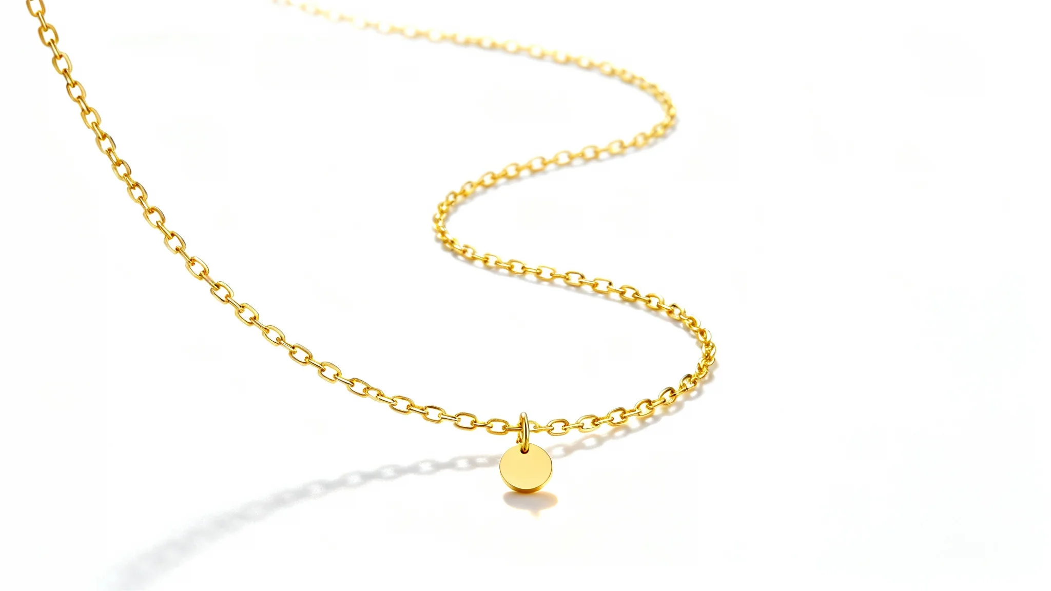 A professional product photograph of a delicate gold necklace with a small, round pendant, elegantly arranged on a clean white background to highlight its luxury.
